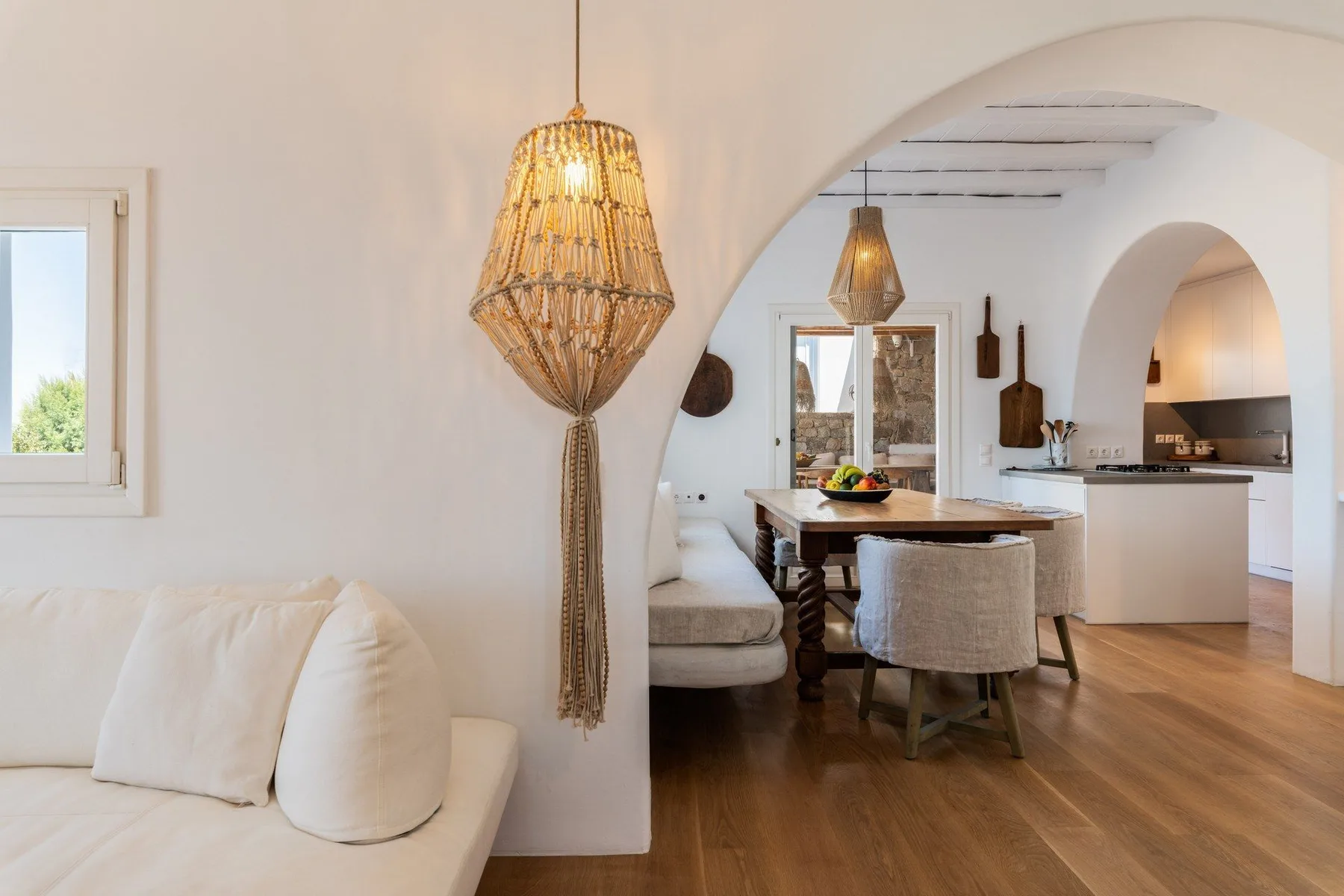 A bright living and dining area opens onto a kitchen, with a pendant lamp in front.