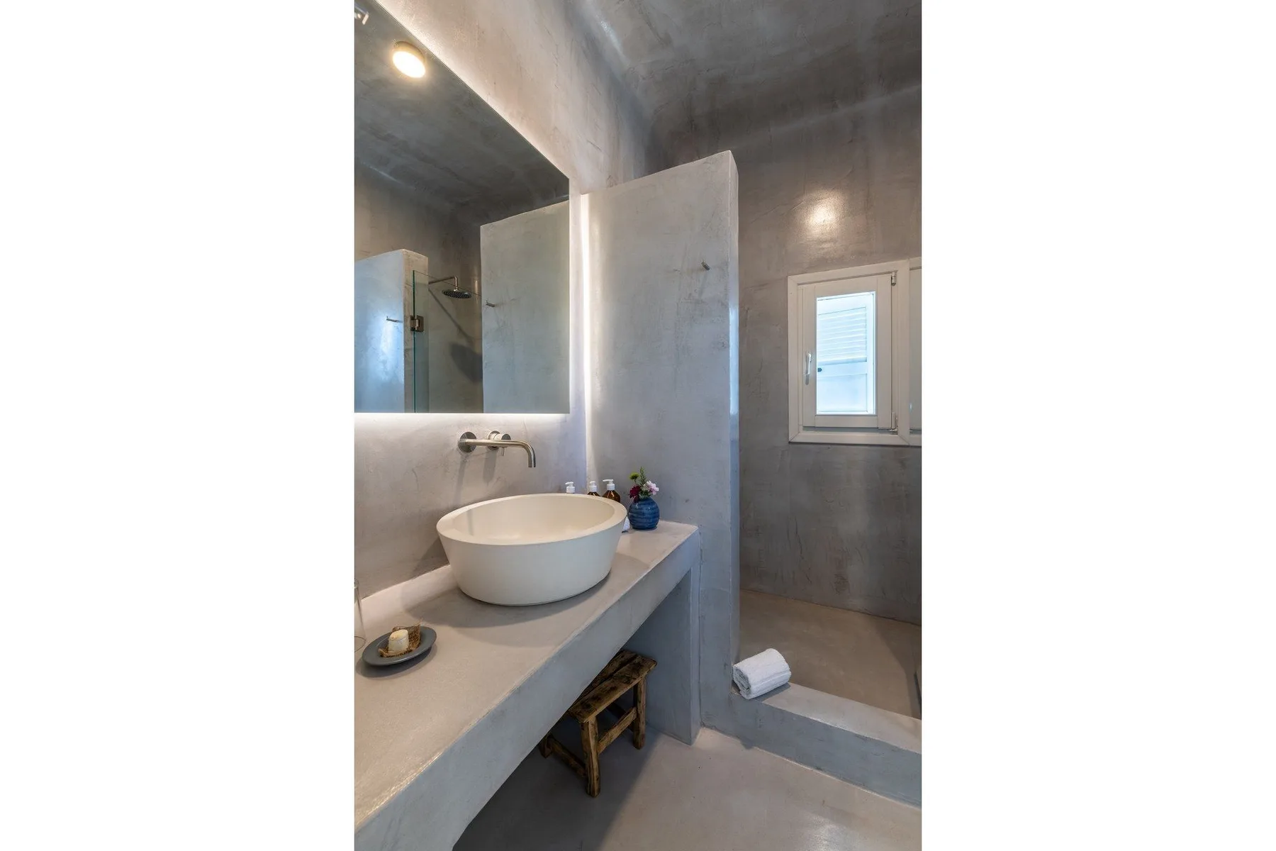 A modern bathroom with a vessel sink, wall mirror, and shower.