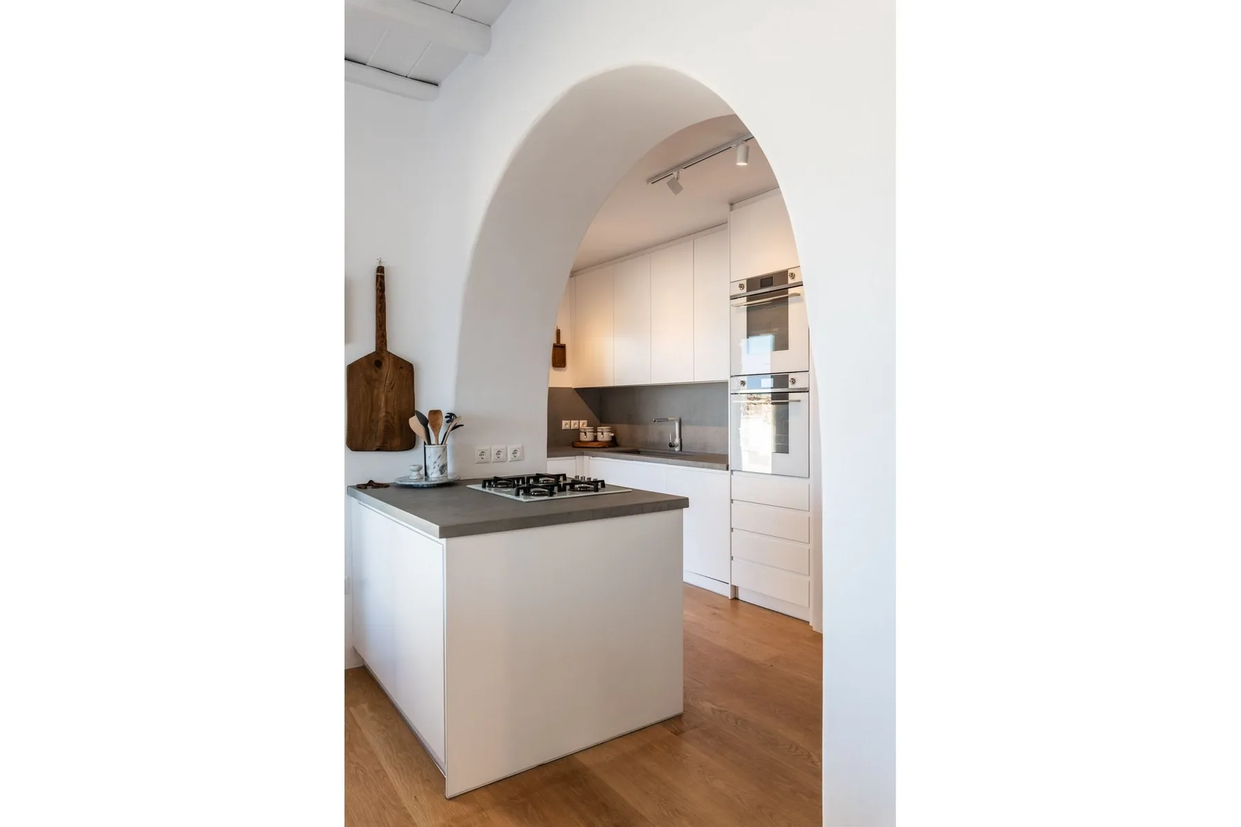 A bright kitchen with white cabinets, a cooking island, and wood flooring.