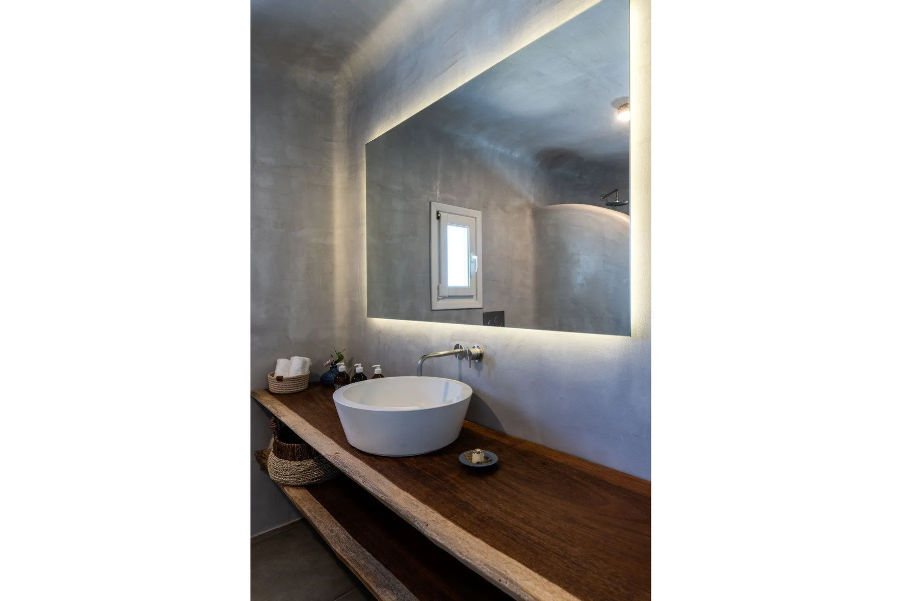 A bathroom vanity with a white vessel sink beneath a large mirror.