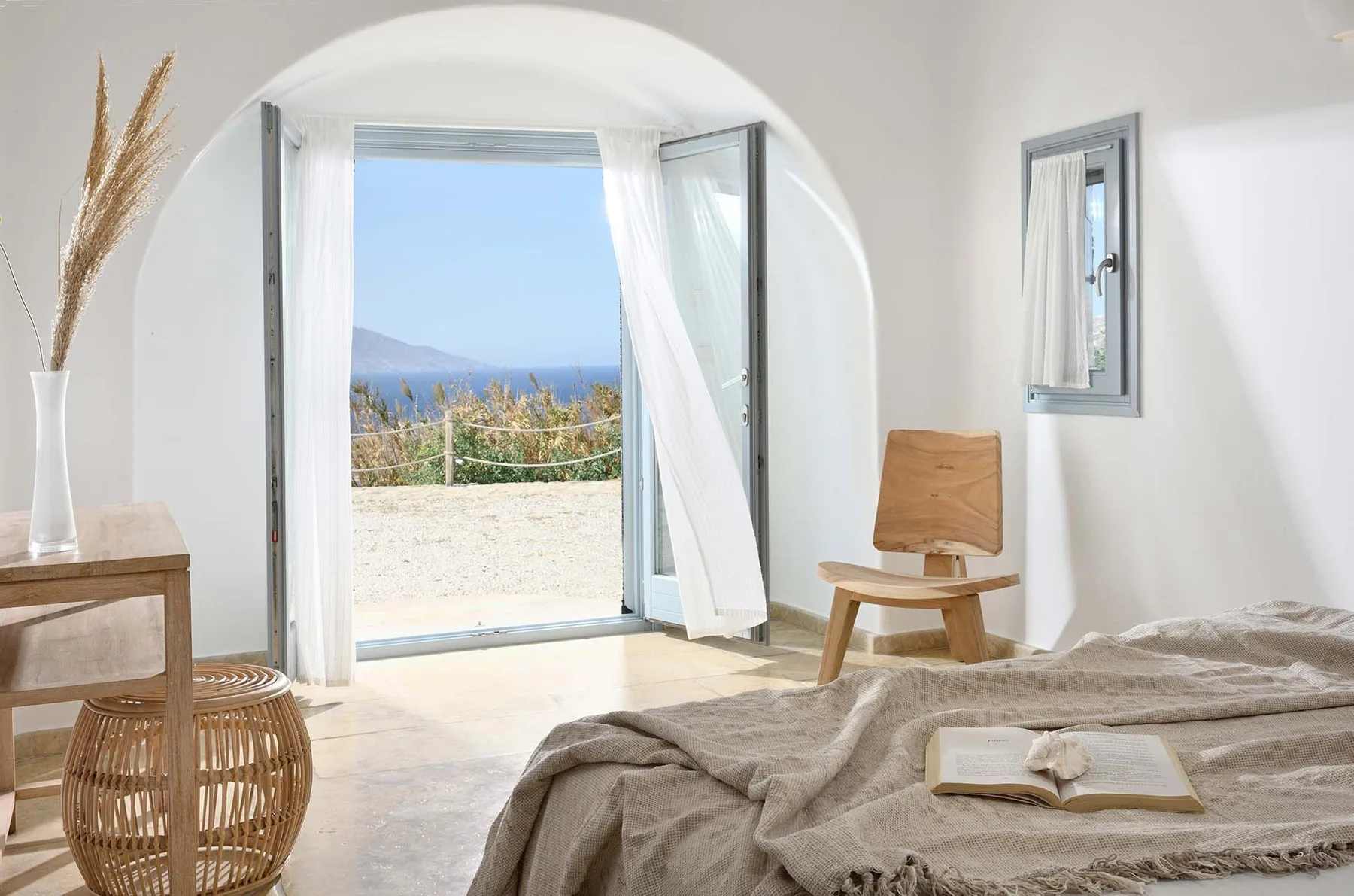 A bright bedroom opens onto a balcony through wide glass doors.