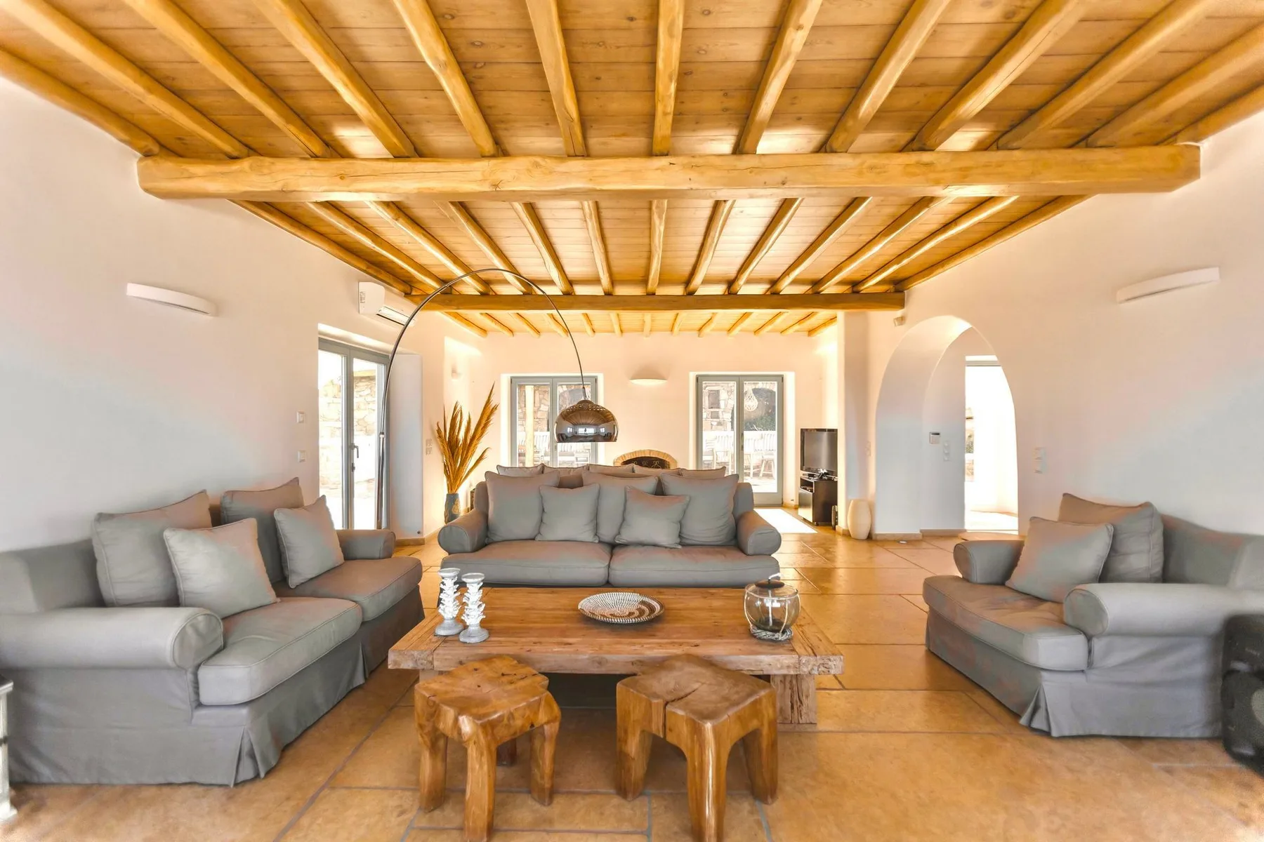 A bright living room with seating beneath a wooden-beam ceiling.