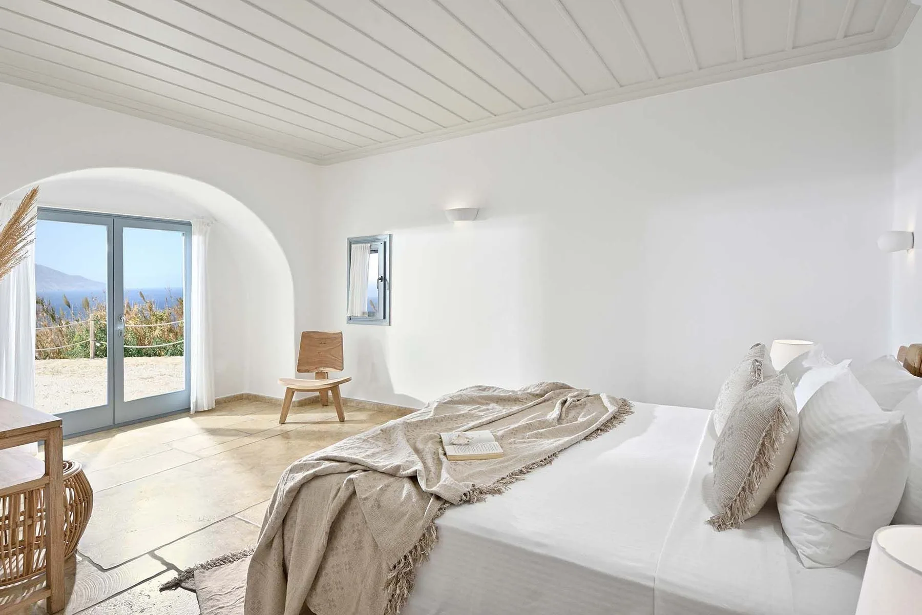 A bright bedroom with a bed and a glass door opening onto a patio.