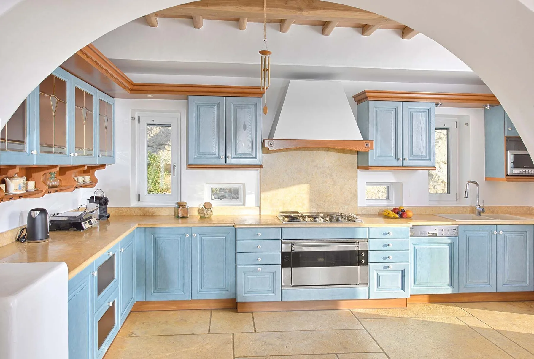 A bright kitchen with blue cabinets, a central range, and a large white hood.