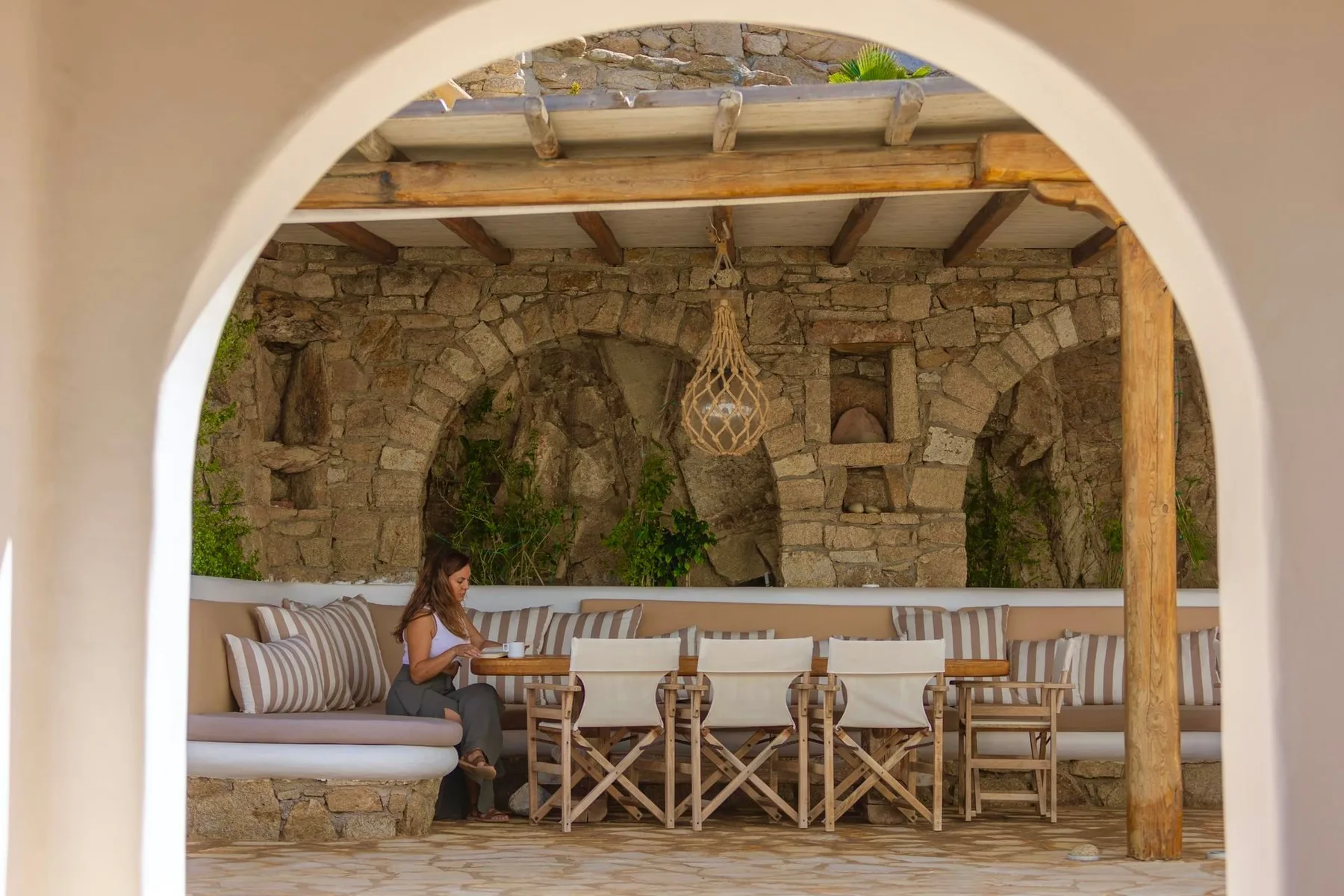 A covered patio with a long cushioned bench and a dining table.