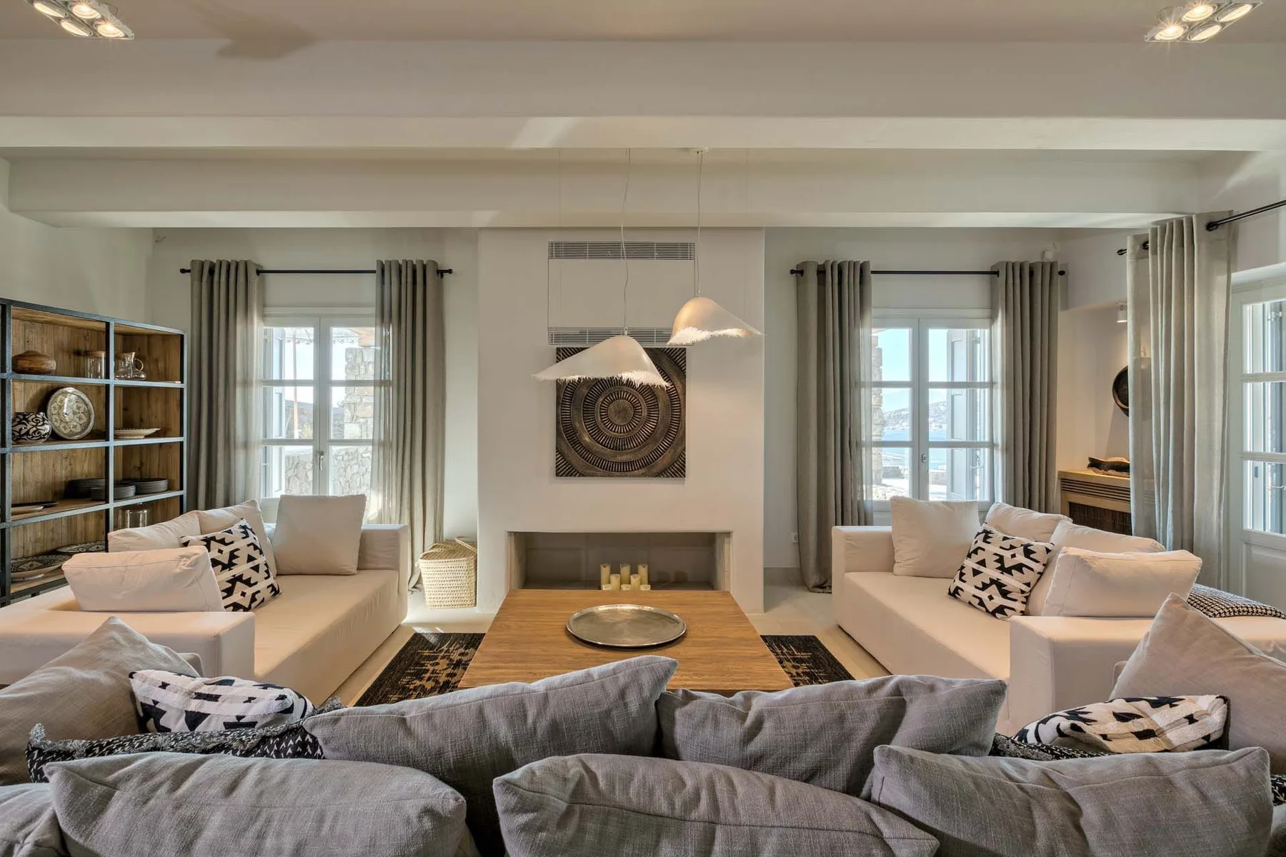 A spacious living room with seating arranged around a central fireplace.