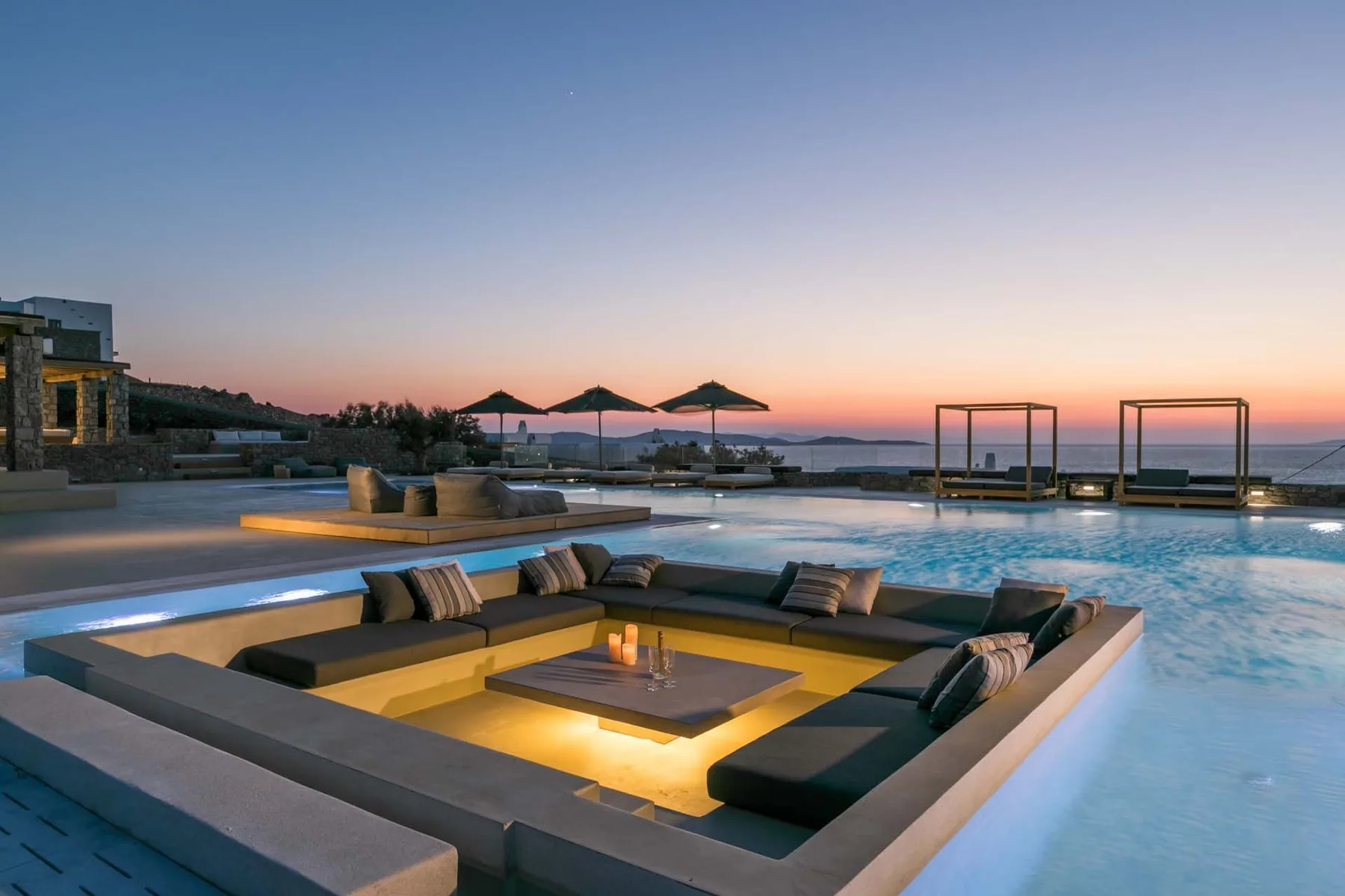 An outdoor swimming pool at dusk with a sunken seating area.