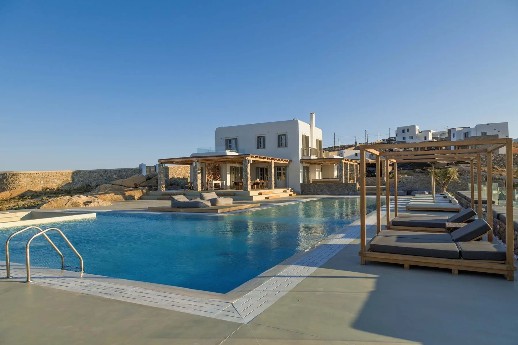 An outdoor pool beside a modern building, with shaded seating along the water.