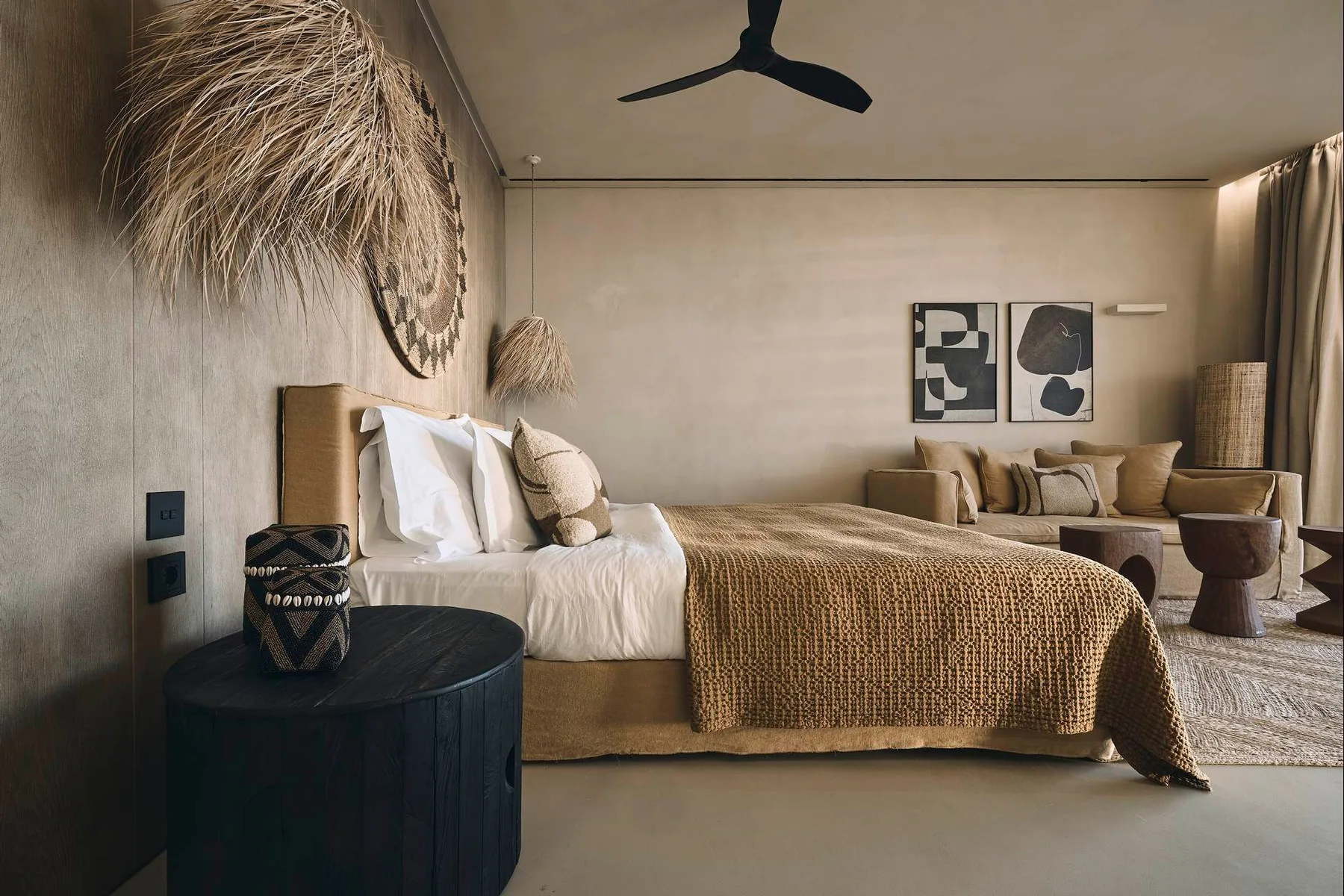 A bedroom with a bed dressed in white linens and a woven brown cover.