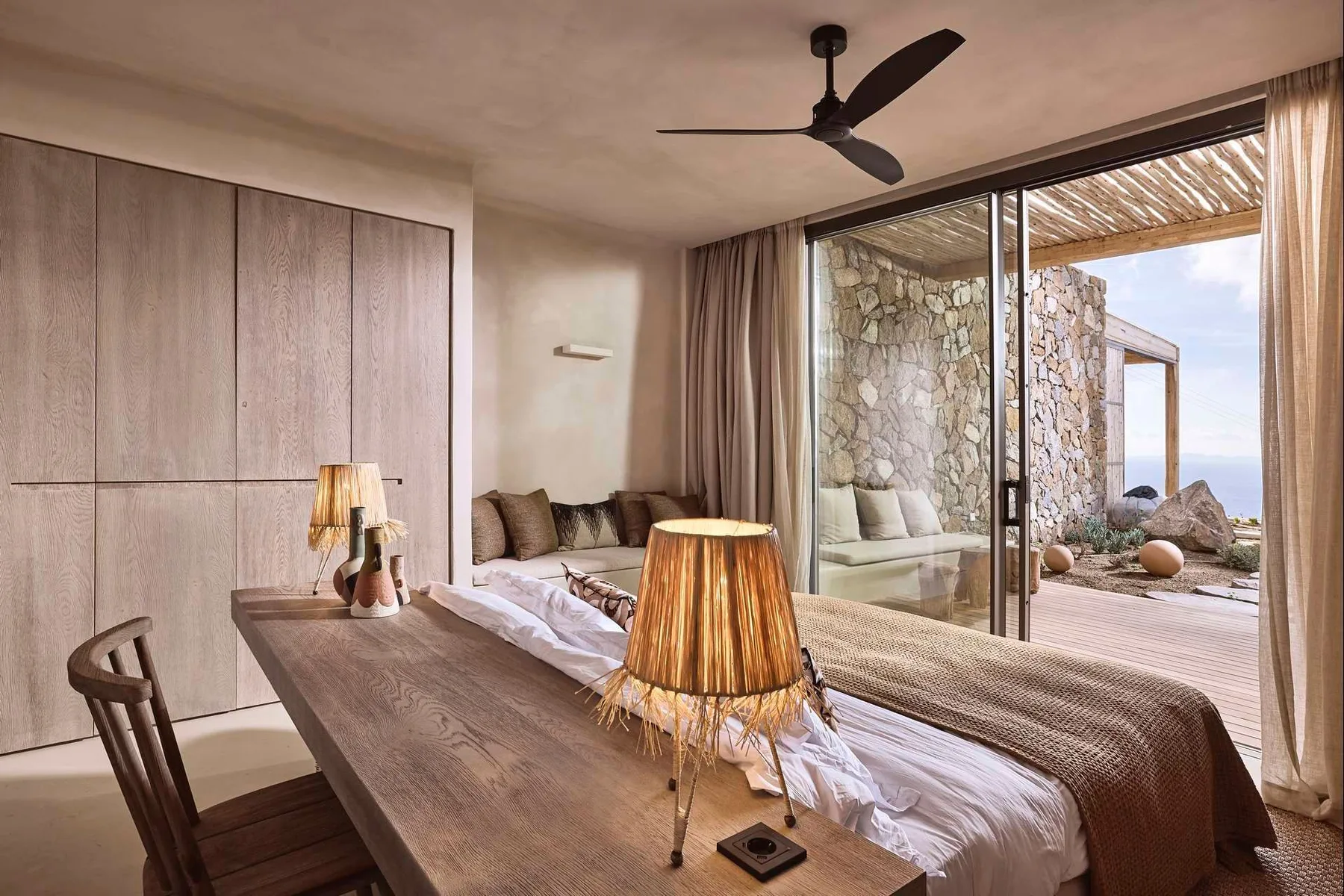 A bedroom with a bed beside wide glass doors opening onto a patio.