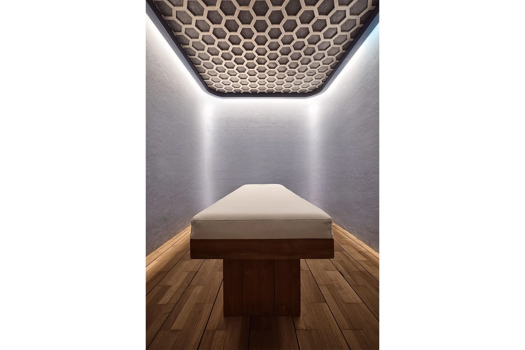 A treatment room with a padded table beneath a patterned ceiling.