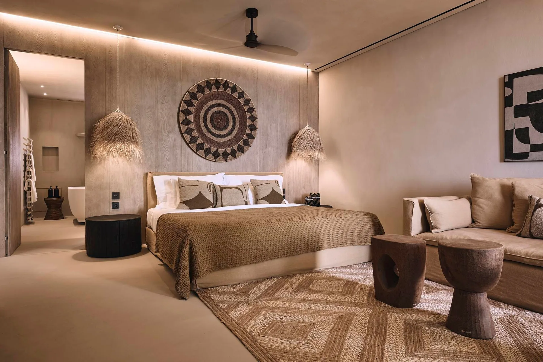 A warm-toned bedroom with a bed, bedside lamps, and woven wall decor.