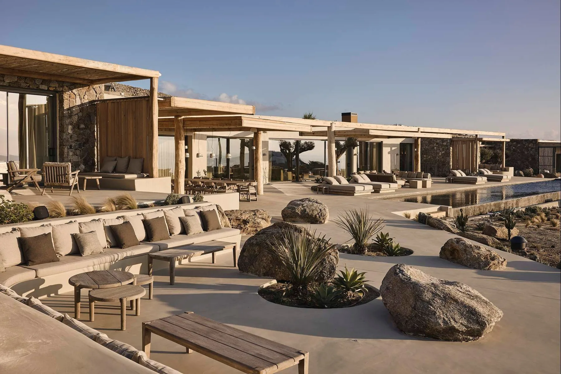 A modern resort terrace with outdoor seating, desert landscaping, and a long pool.
