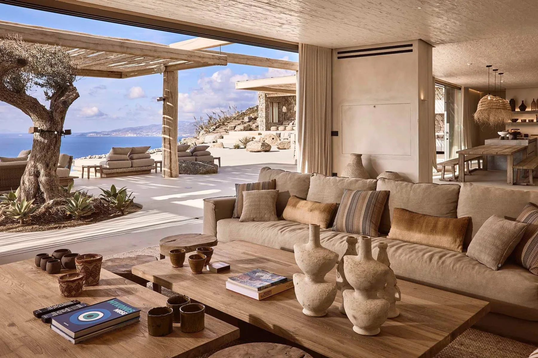 An open-plan living room with a seating area overlooking a terrace and the sea.