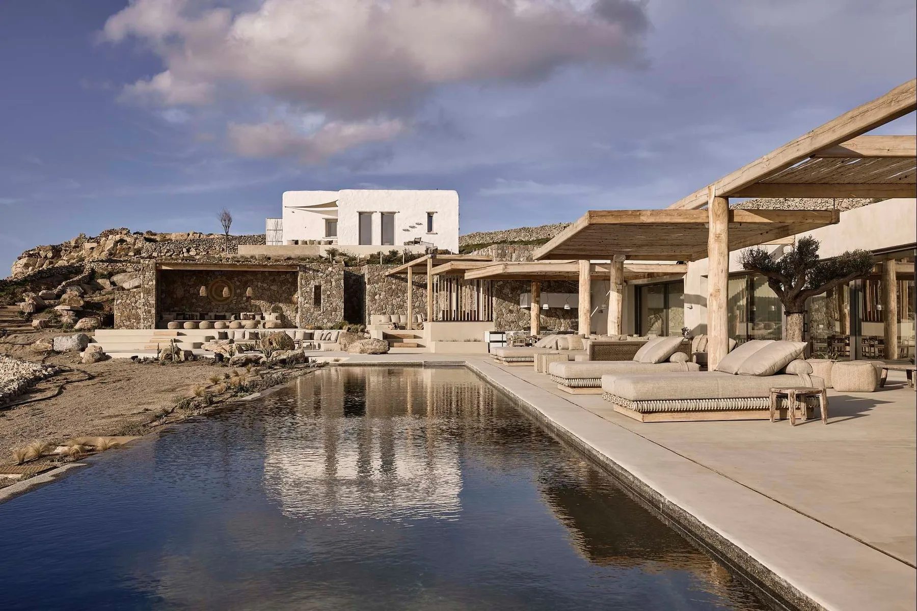 A modern outdoor pool beside a spacious stone-and-wood terrace.
