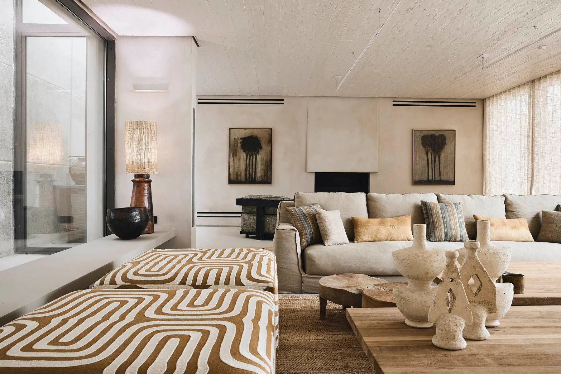 A bright living room with a sofa, patterned ottoman, and coffee table.