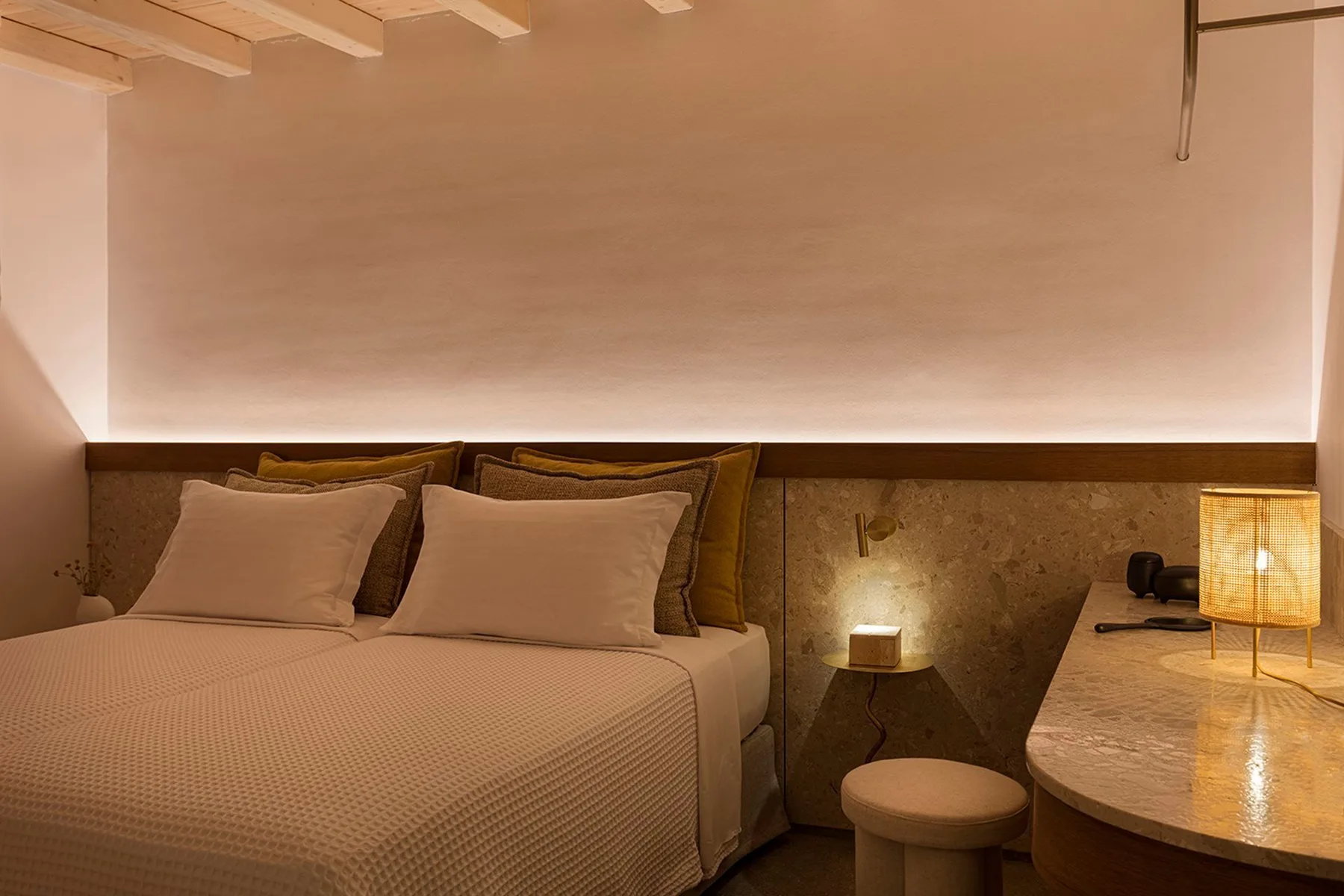 A bedroom with a neatly made bed and a desk beside it.