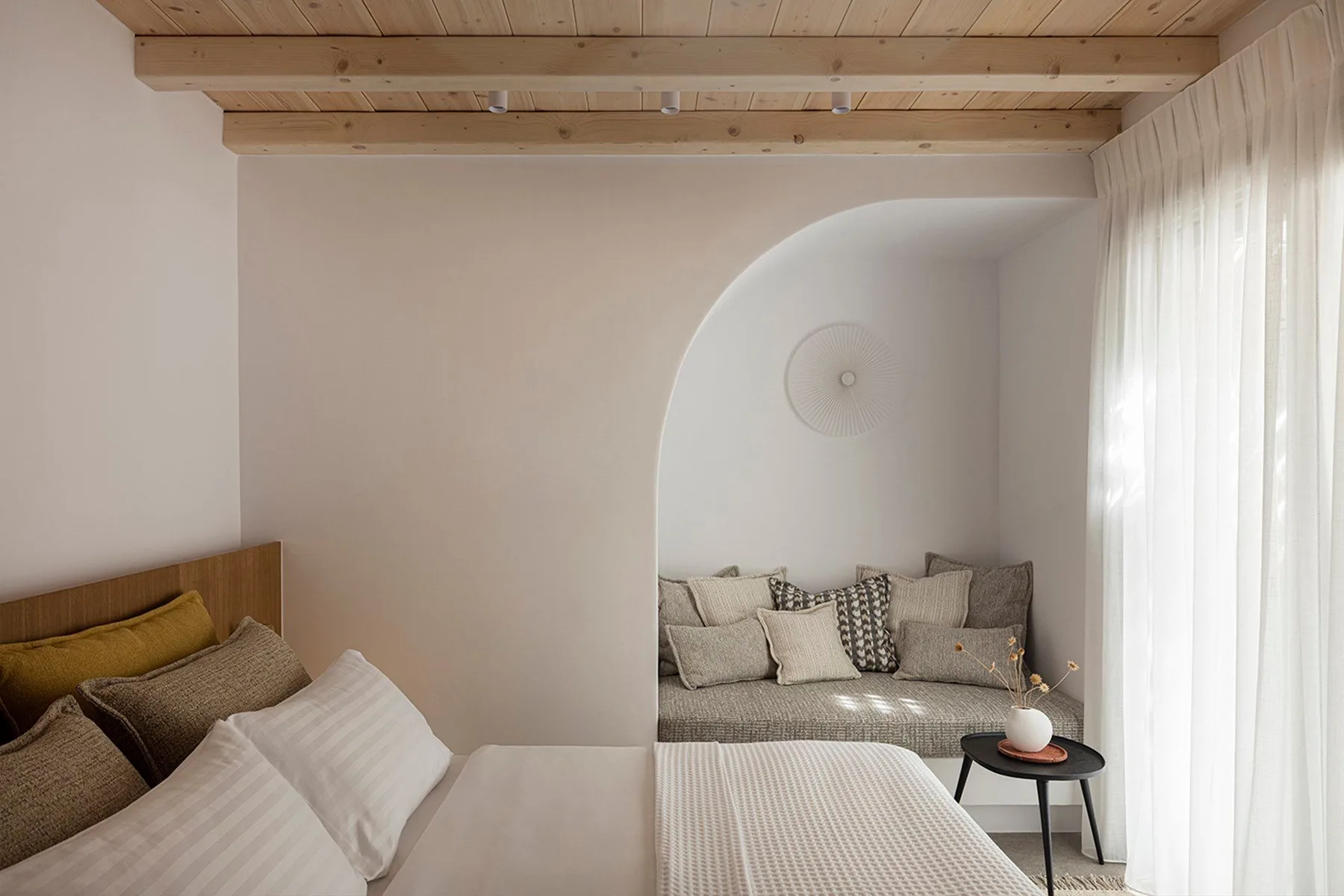 A bedroom with a bed and a sitting area set within an arched alcove.