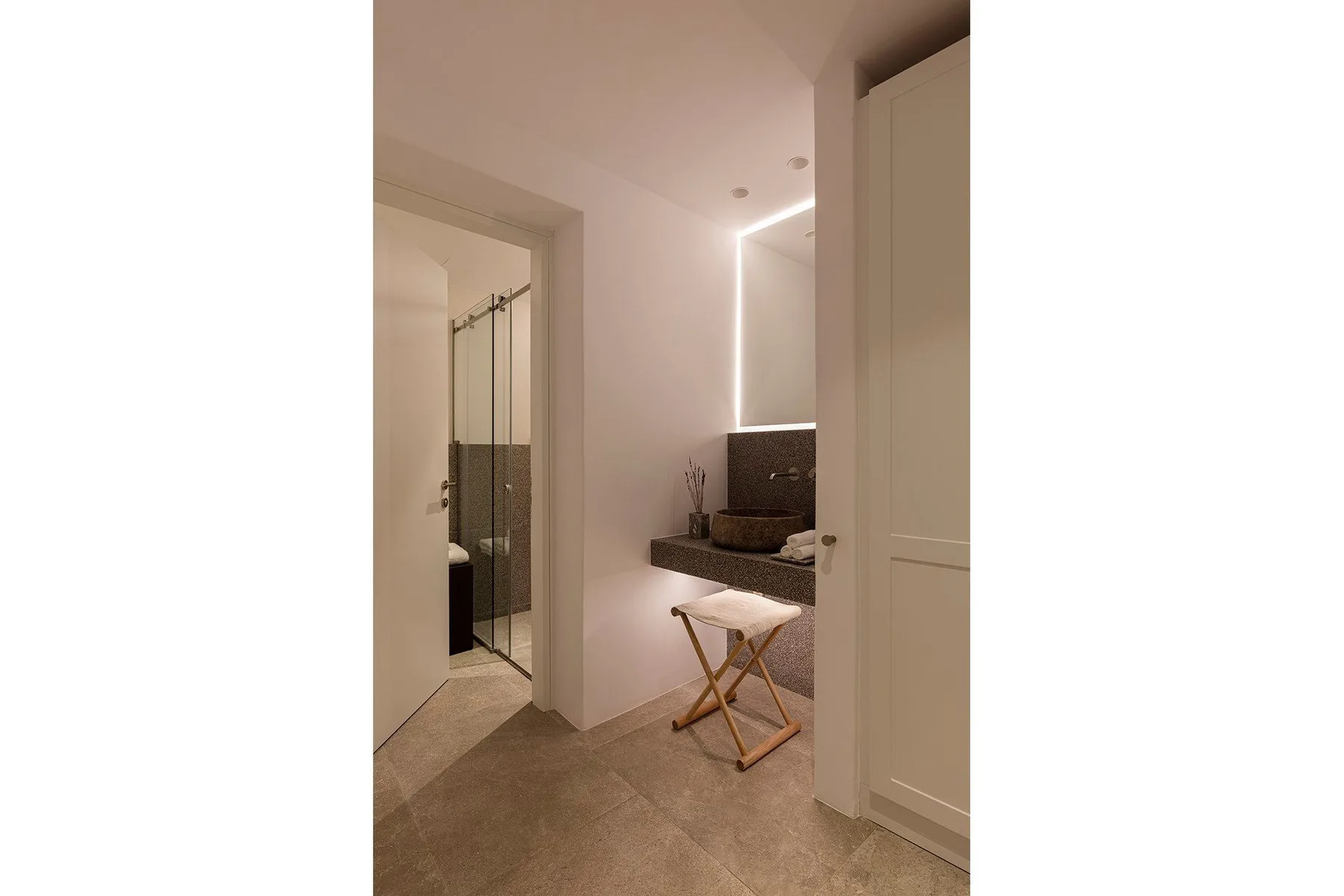 A bathroom vanity with a vessel sink sits beside a glass shower.