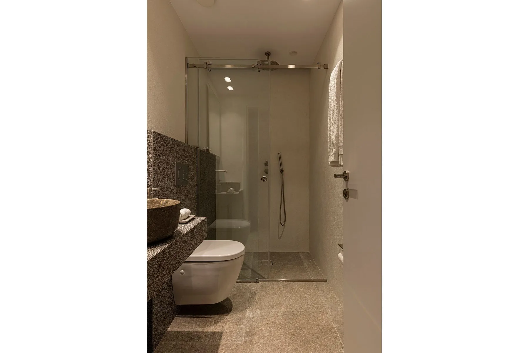A bathroom with a glass shower and a toilet beside the vanity.