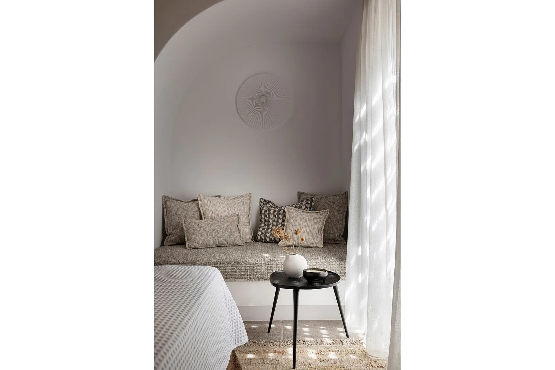 A bedroom seating nook with patterned cushions and a small round table.