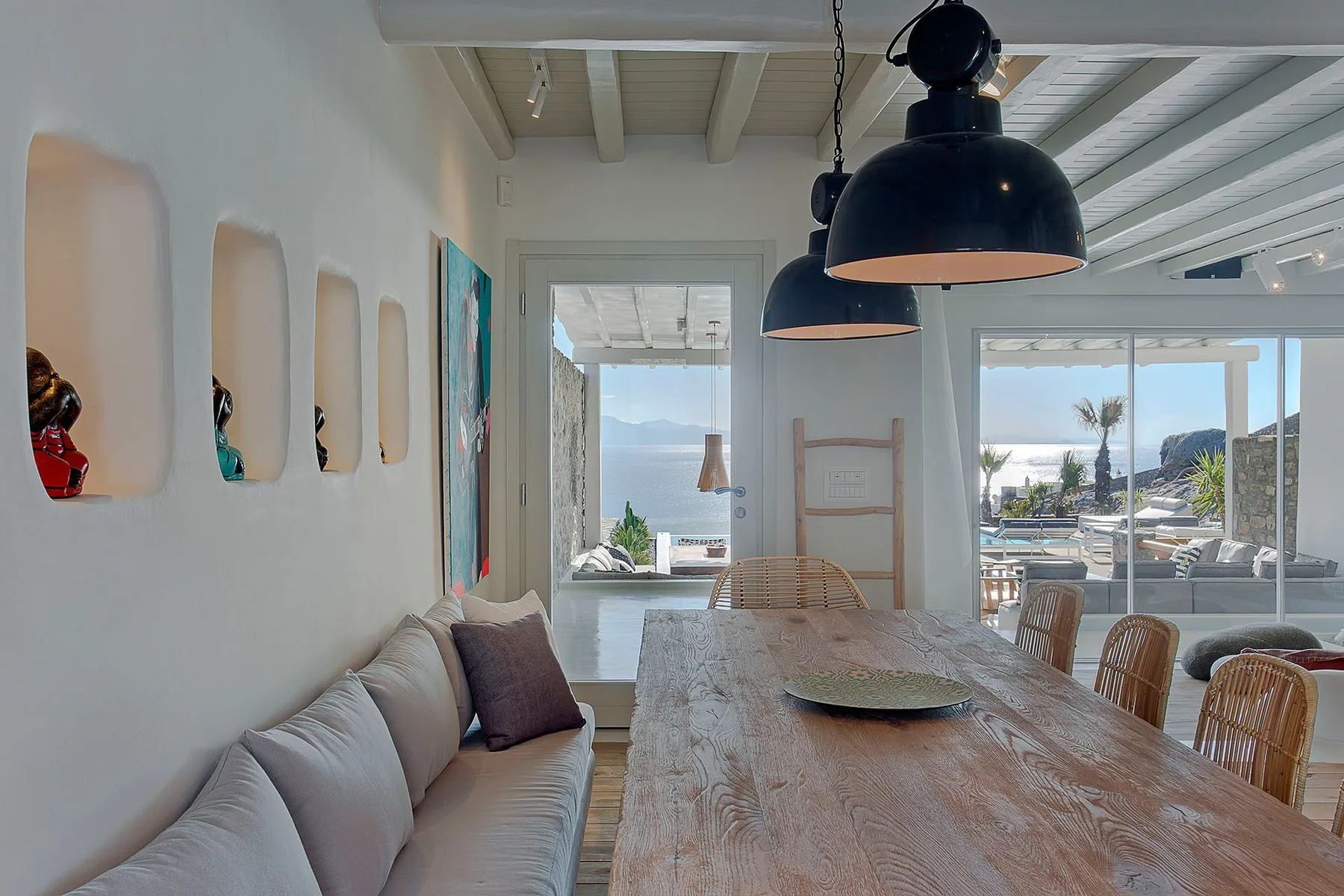 A bright dining area with a long wooden table beside a living-room seating area.