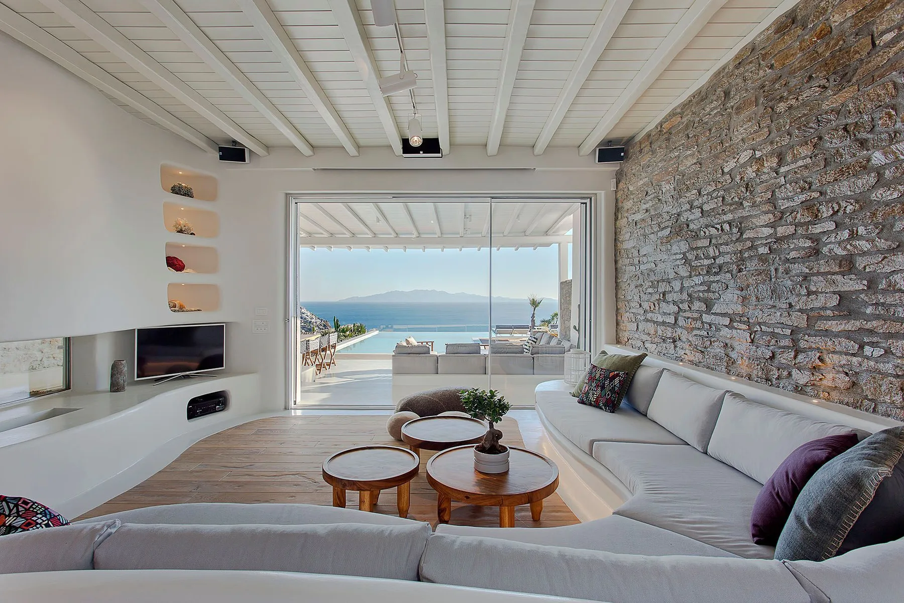 A bright living room with seating and a large window overlooking the water.