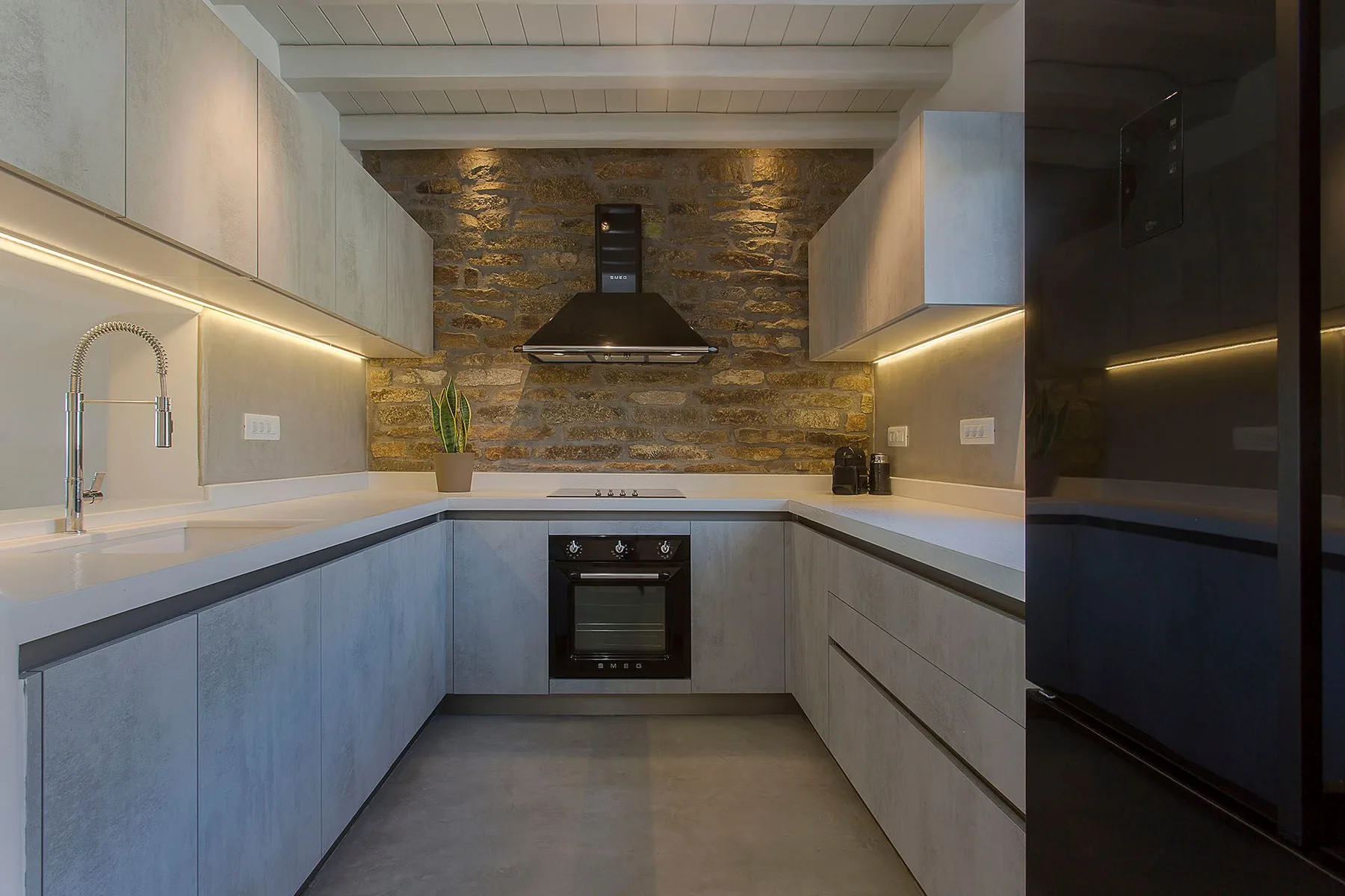 A modern kitchen with light cabinetry and a stone backsplash.