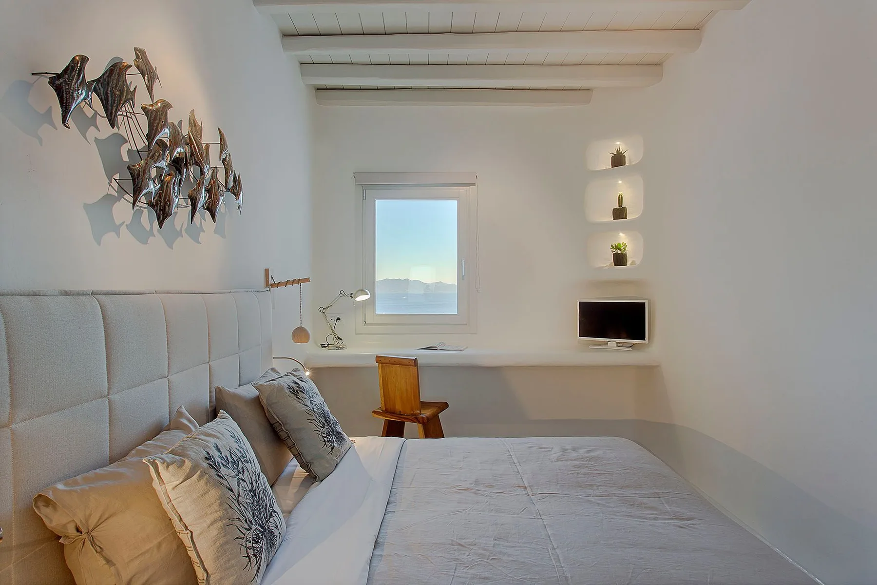 A bedroom with a bed, a desk beneath the window, and wall-mounted decor.