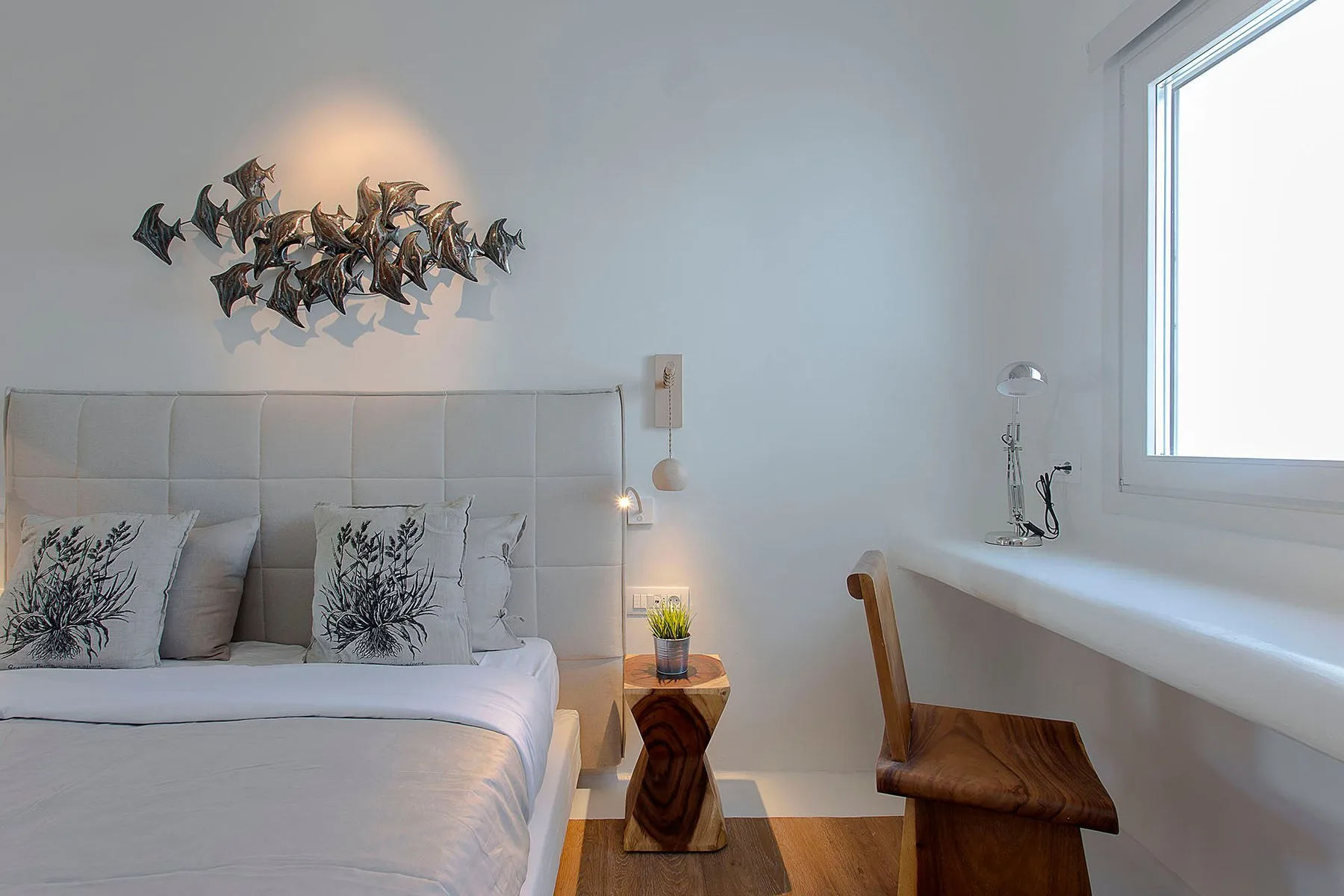 A bedroom with a bed beside a window and a small wooden table.