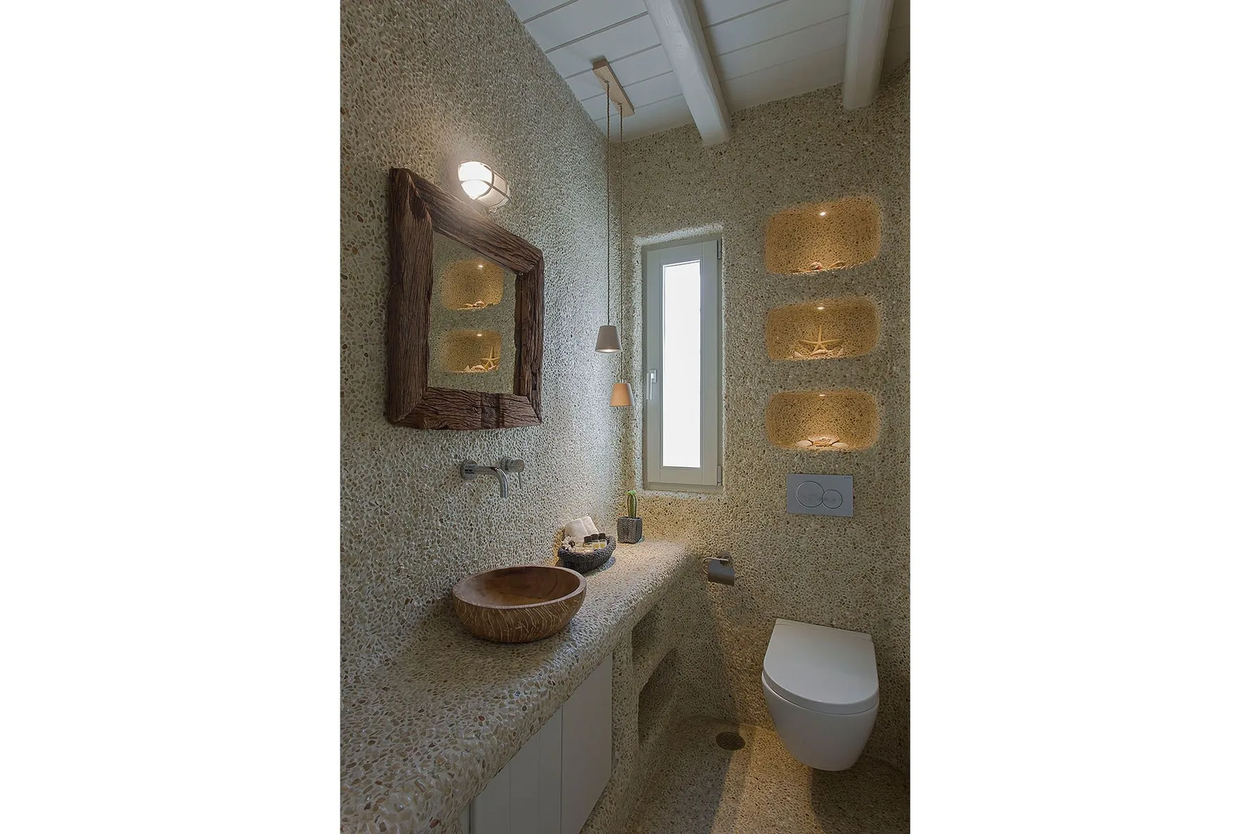 A compact bathroom with a vessel sink, toilet, and narrow window.