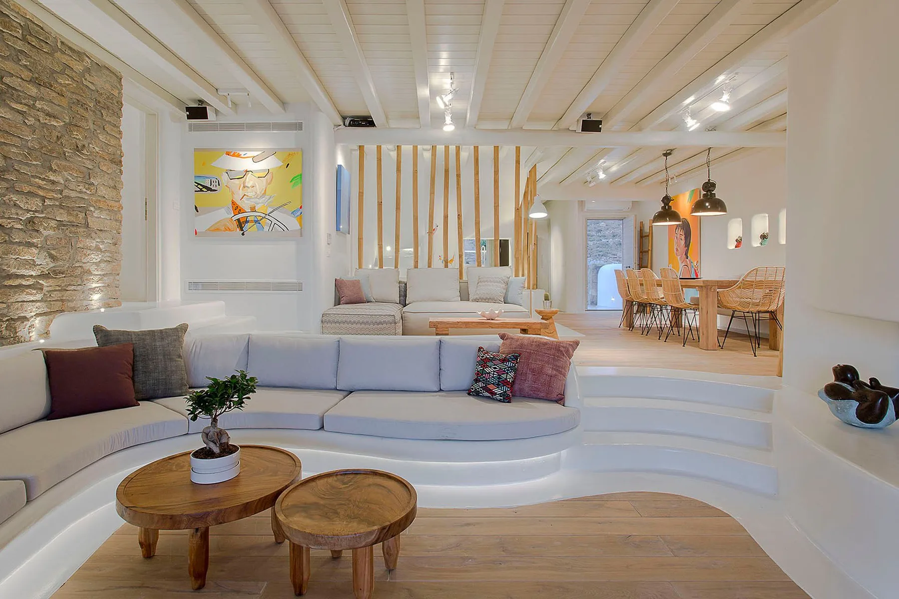 A bright living room with curved seating and an adjoining dining area.