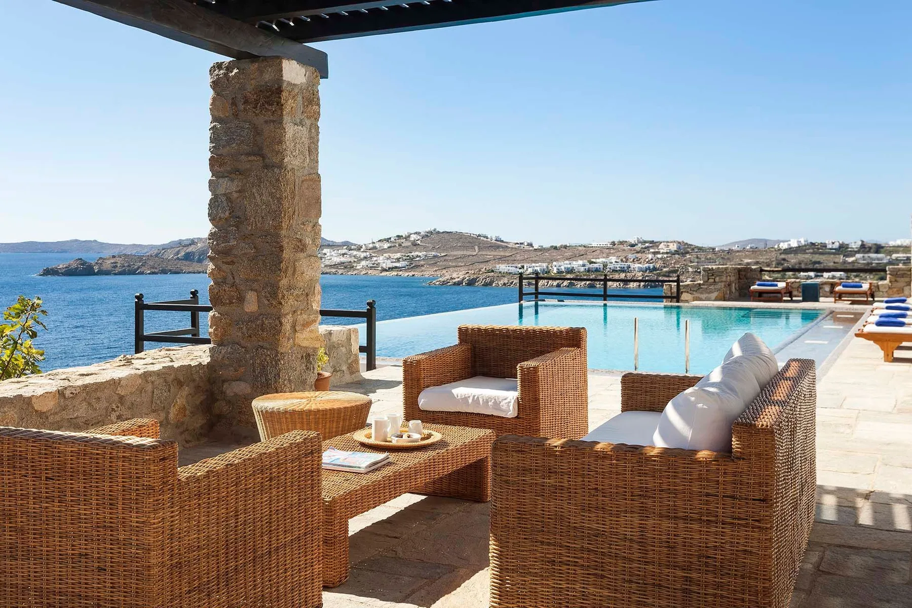 An outdoor seating area overlooks a pool and the sea.
