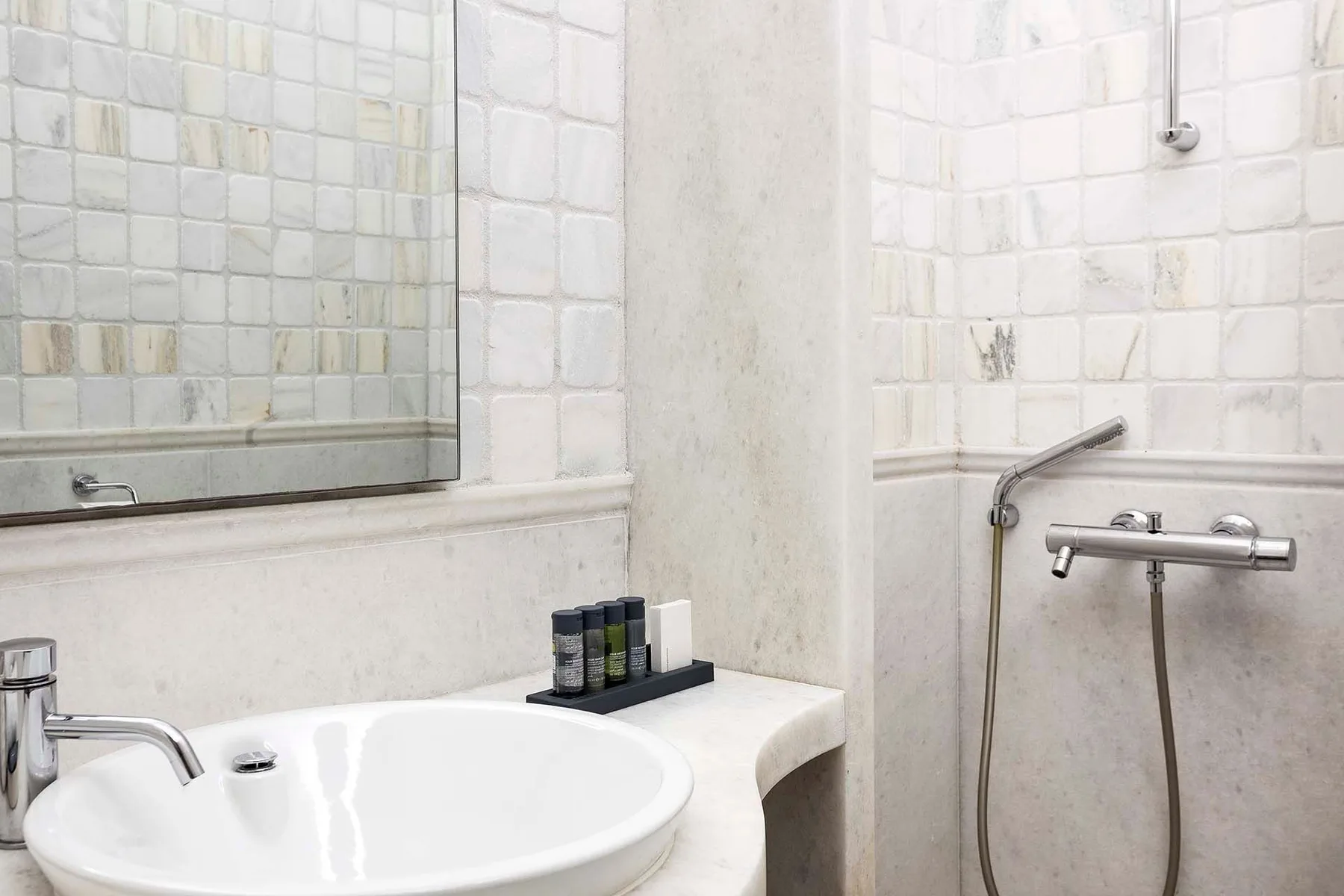 A bathroom with a sink and a wall-mounted shower.