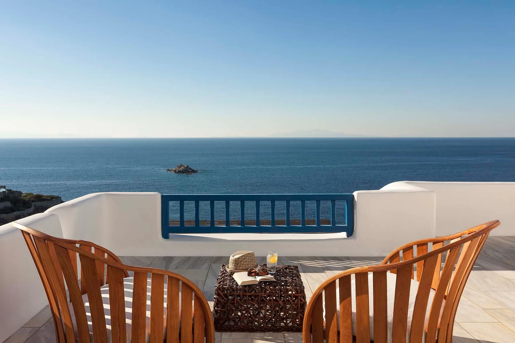 A seaside terrace with wooden seating faces the open water.