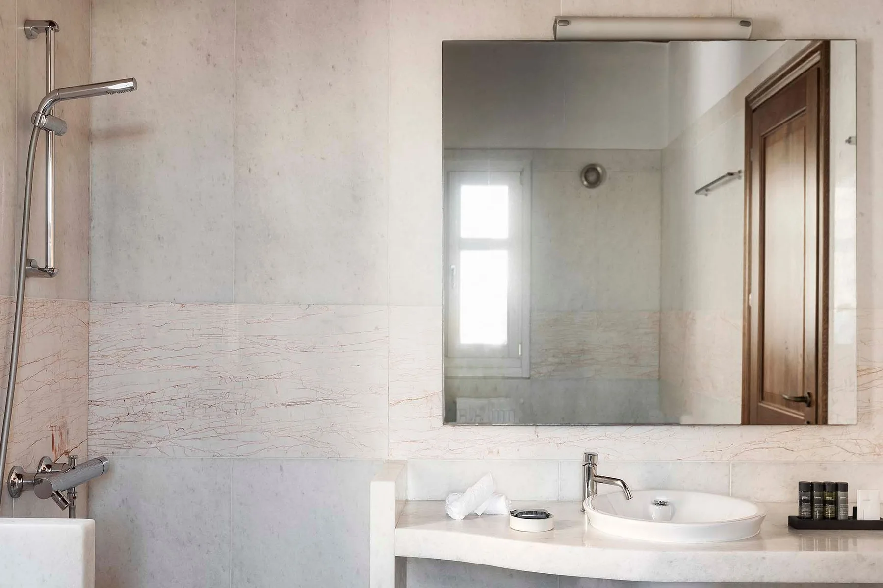 A bathroom vanity with a sink and mirror beside a shower.