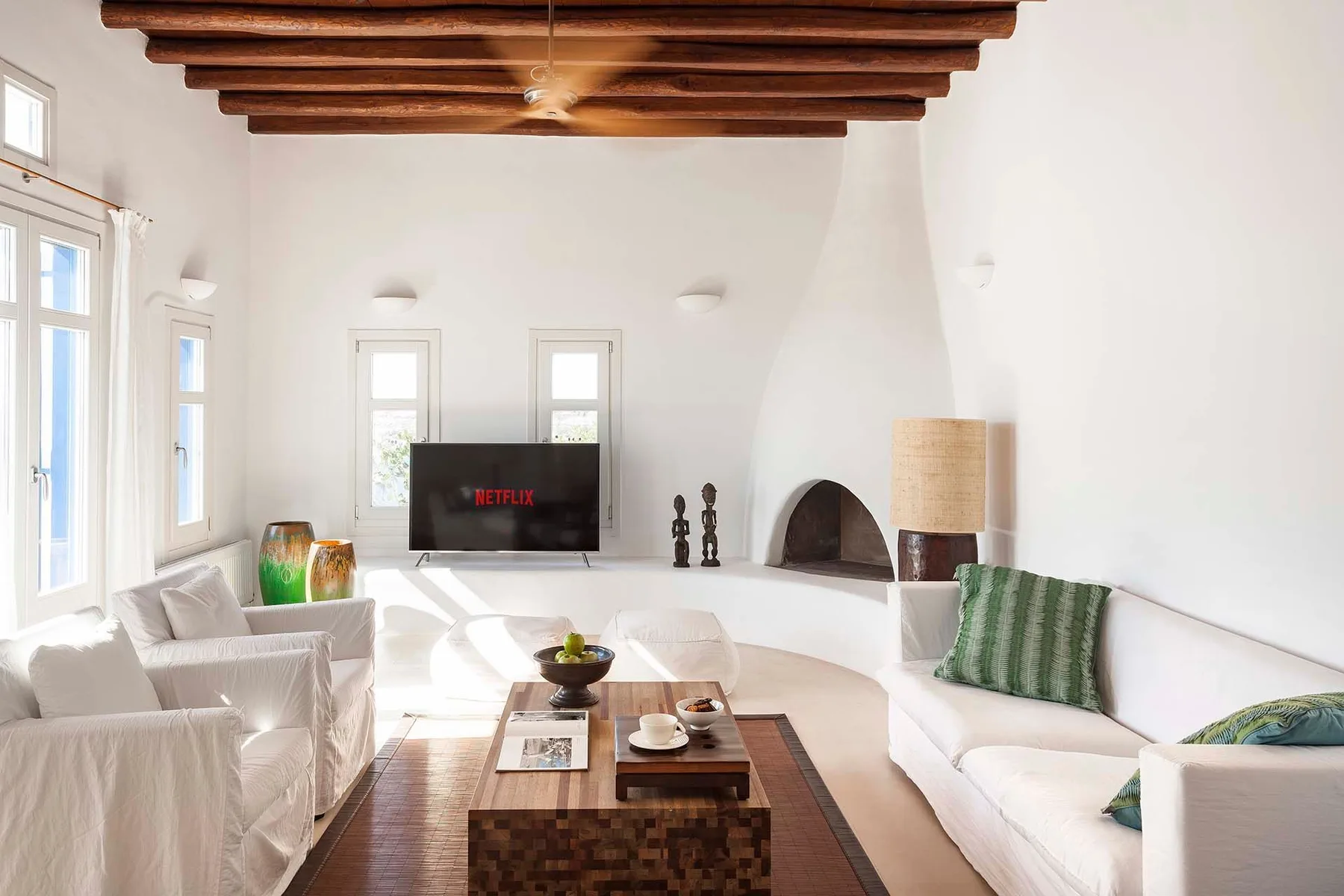 A bright living room with white seating, a low table, and a television.