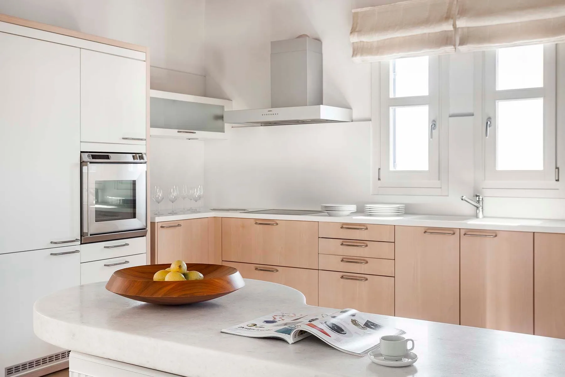 A bright kitchen with pale wood cabinets and a white island.