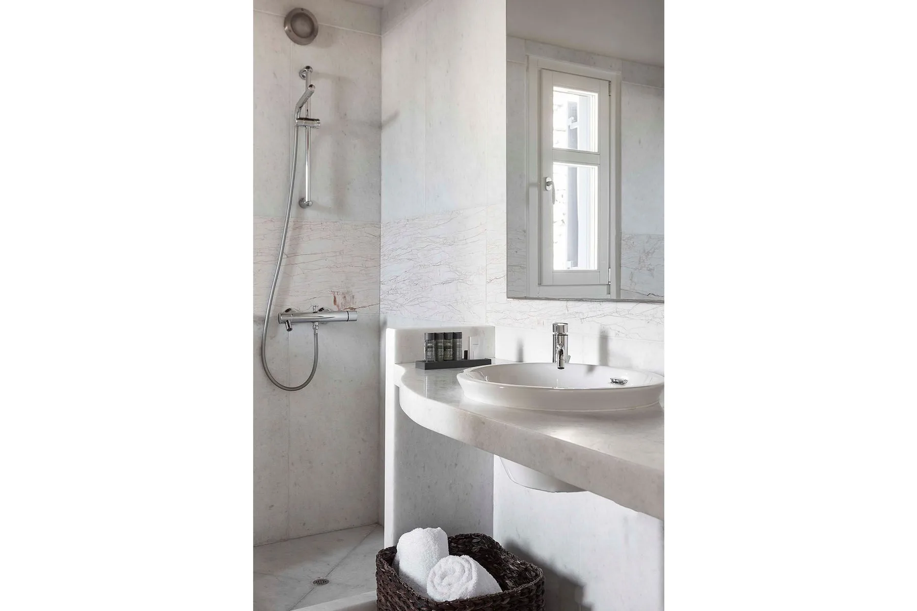A bright bathroom with a shower, sink, and window.