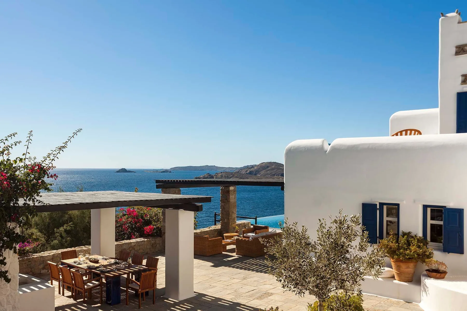 A seaside patio has an outdoor dining area overlooking the water.