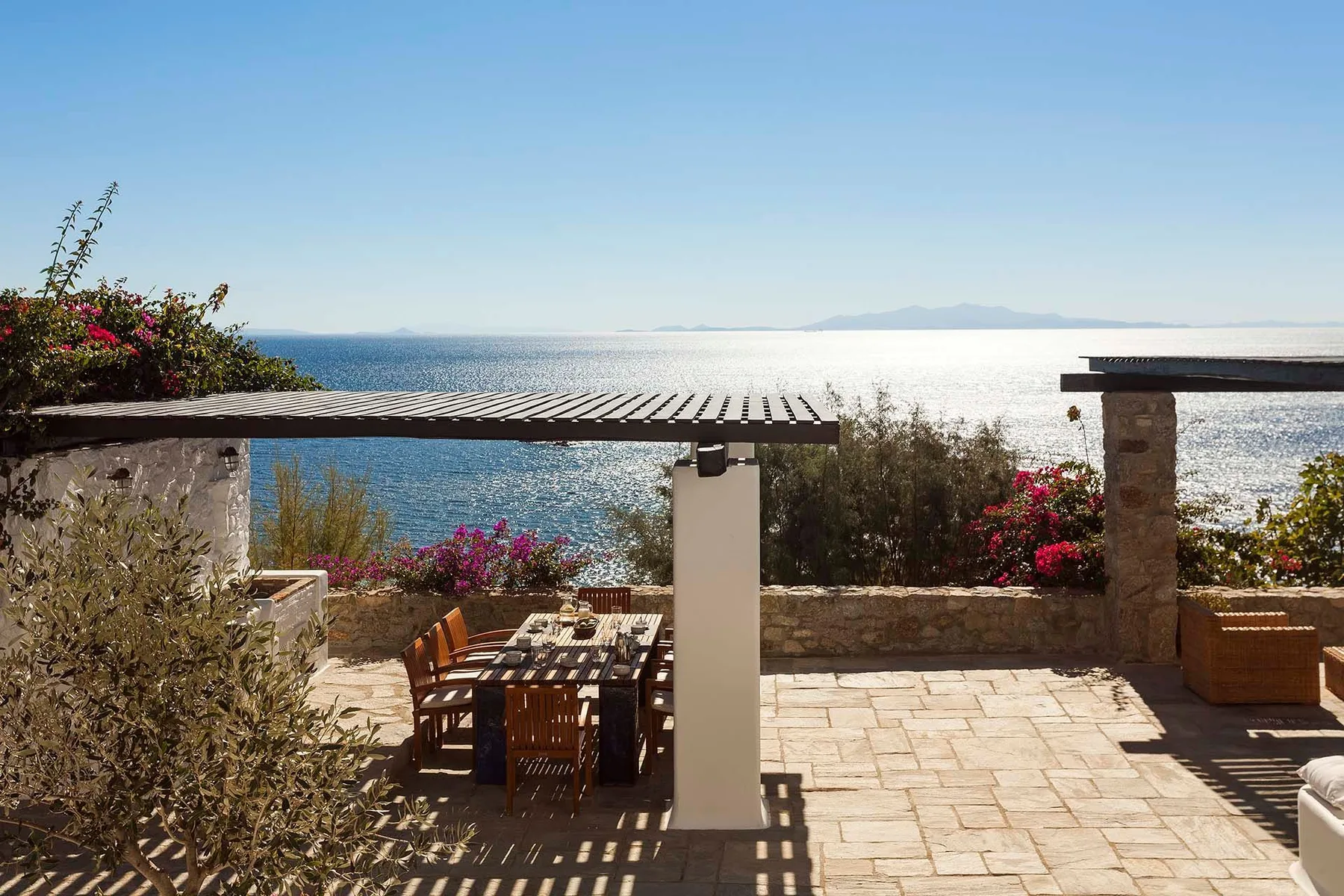 A seaside patio with an outdoor dining table and a view of the water.