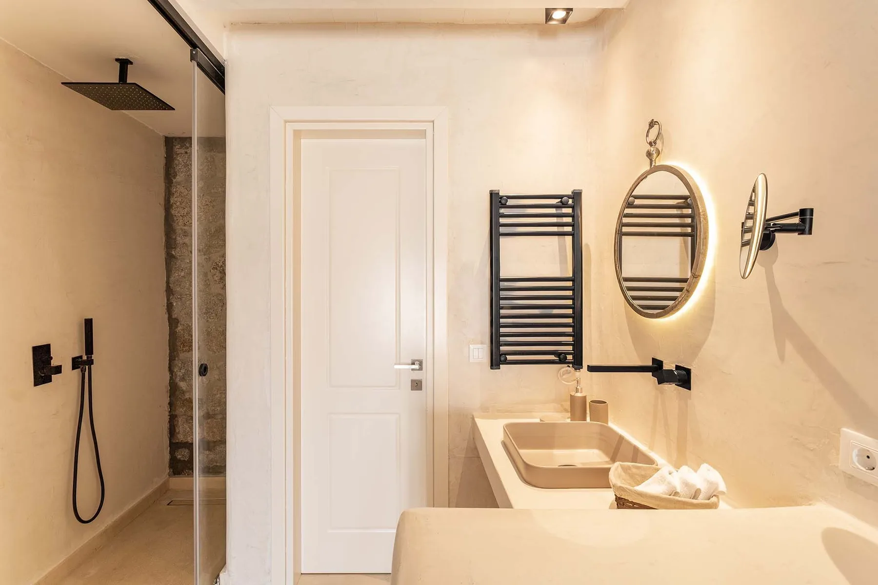 A bathroom with a walk-in shower, sink, and wall-mounted towel warmer.