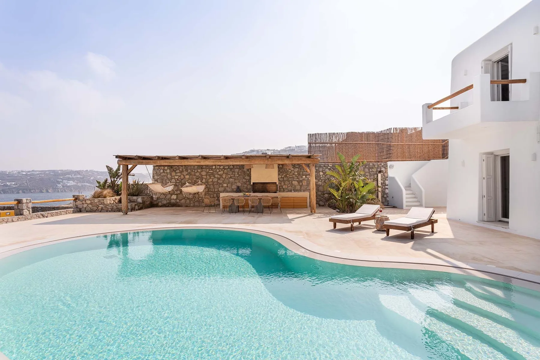 An outdoor swimming pool beside a white building, with lounge seating on the deck.