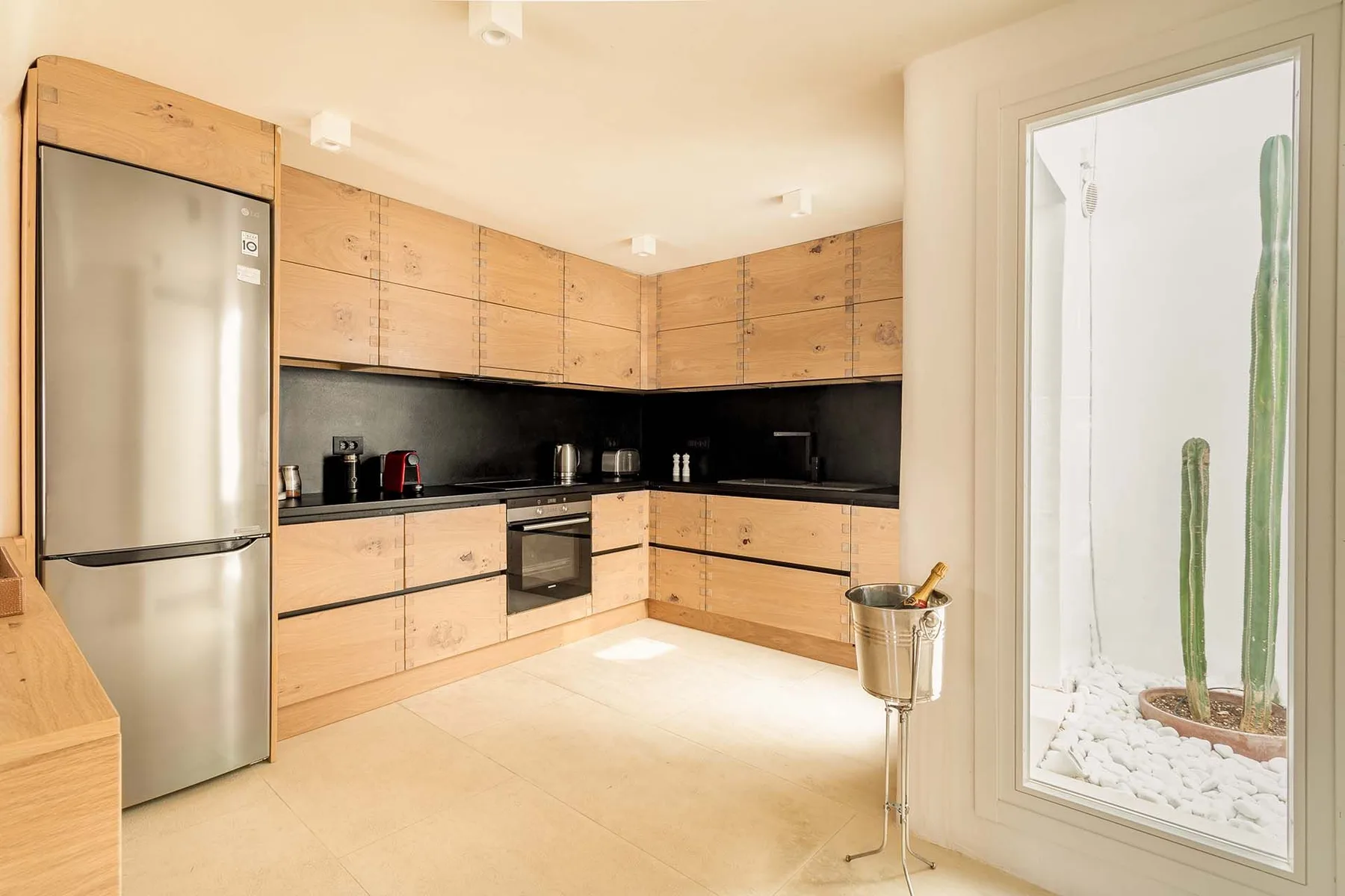 A modern kitchen with wooden cabinetry and a stainless steel refrigerator.