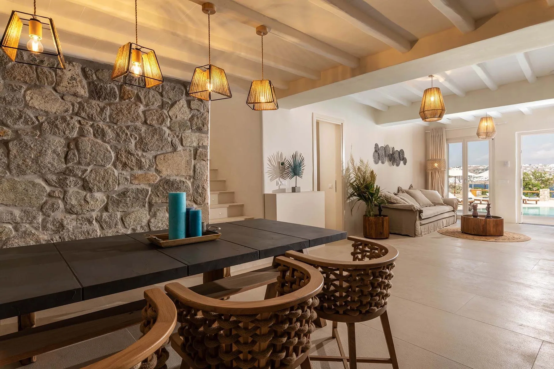 An open living and dining area with a stone feature wall and pendant lights.