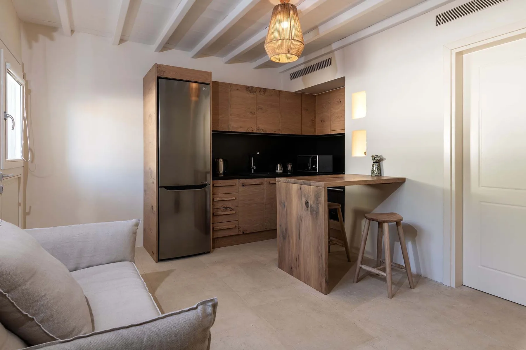 A compact kitchen with wooden cabinets, a counter, and nearby seating.