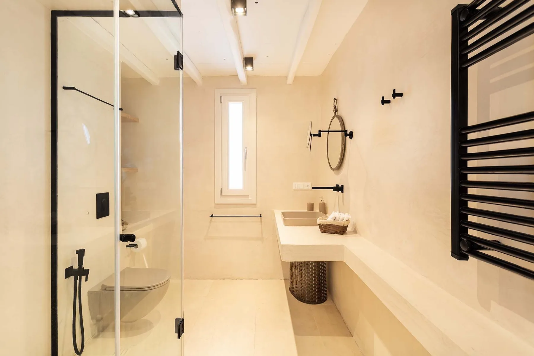 A bright bathroom with a glass shower and a long vanity.