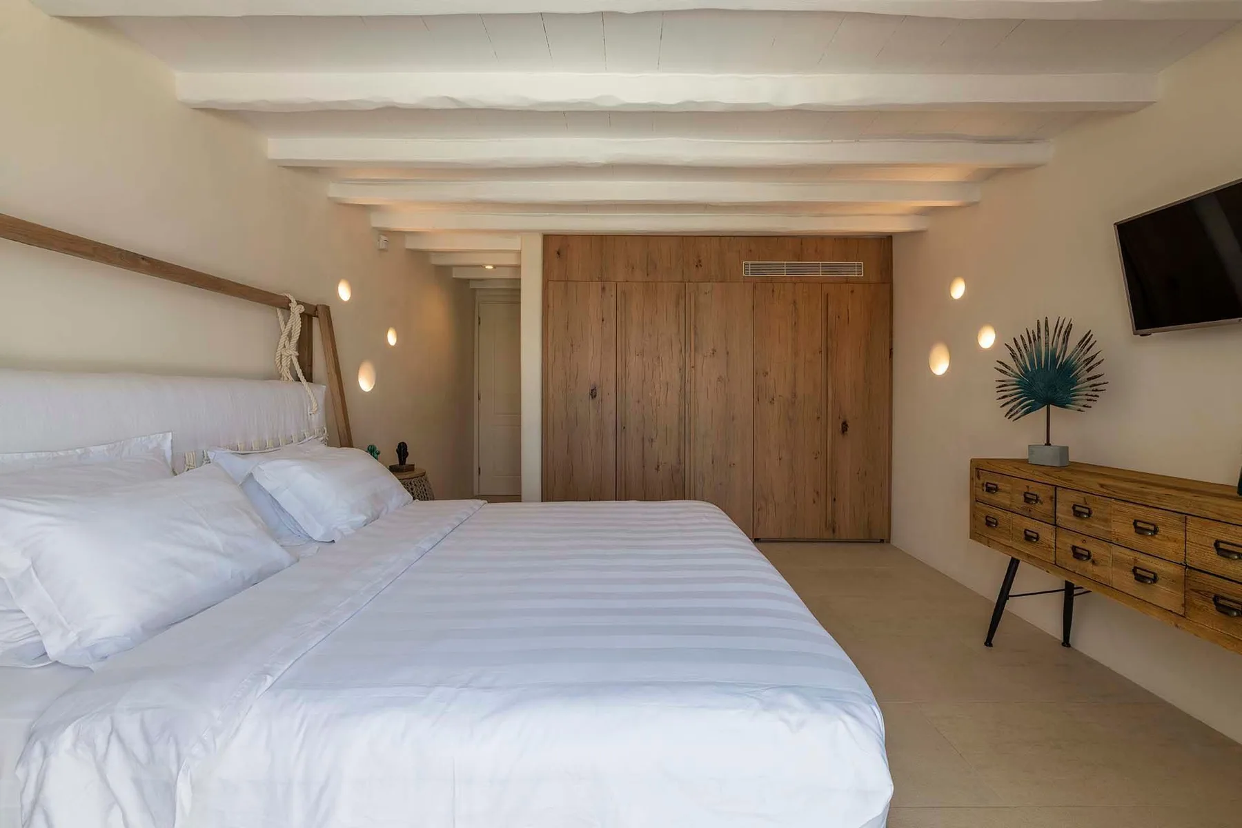 A bedroom with a neatly made bed and a wooden wardrobe.
