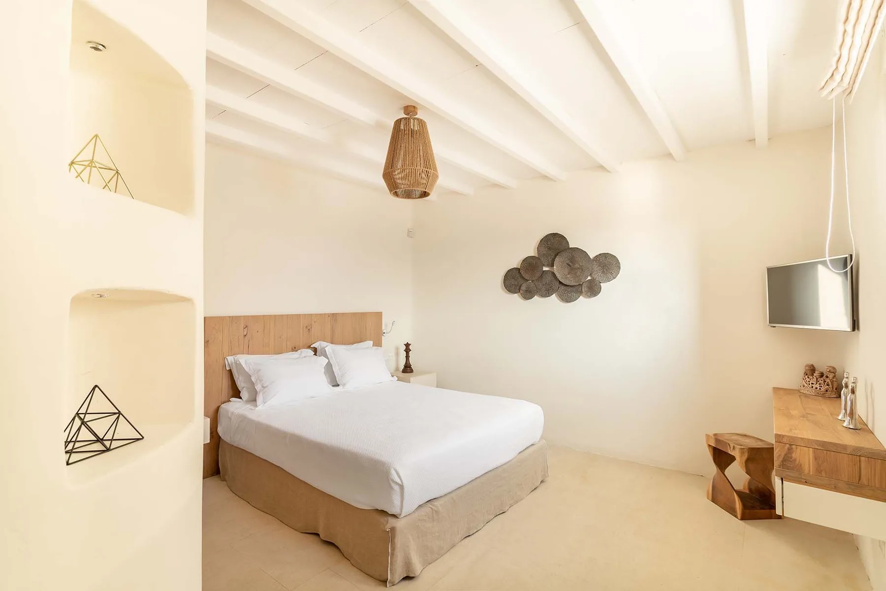 A bright bedroom with a neatly made bed and decorative wall art.