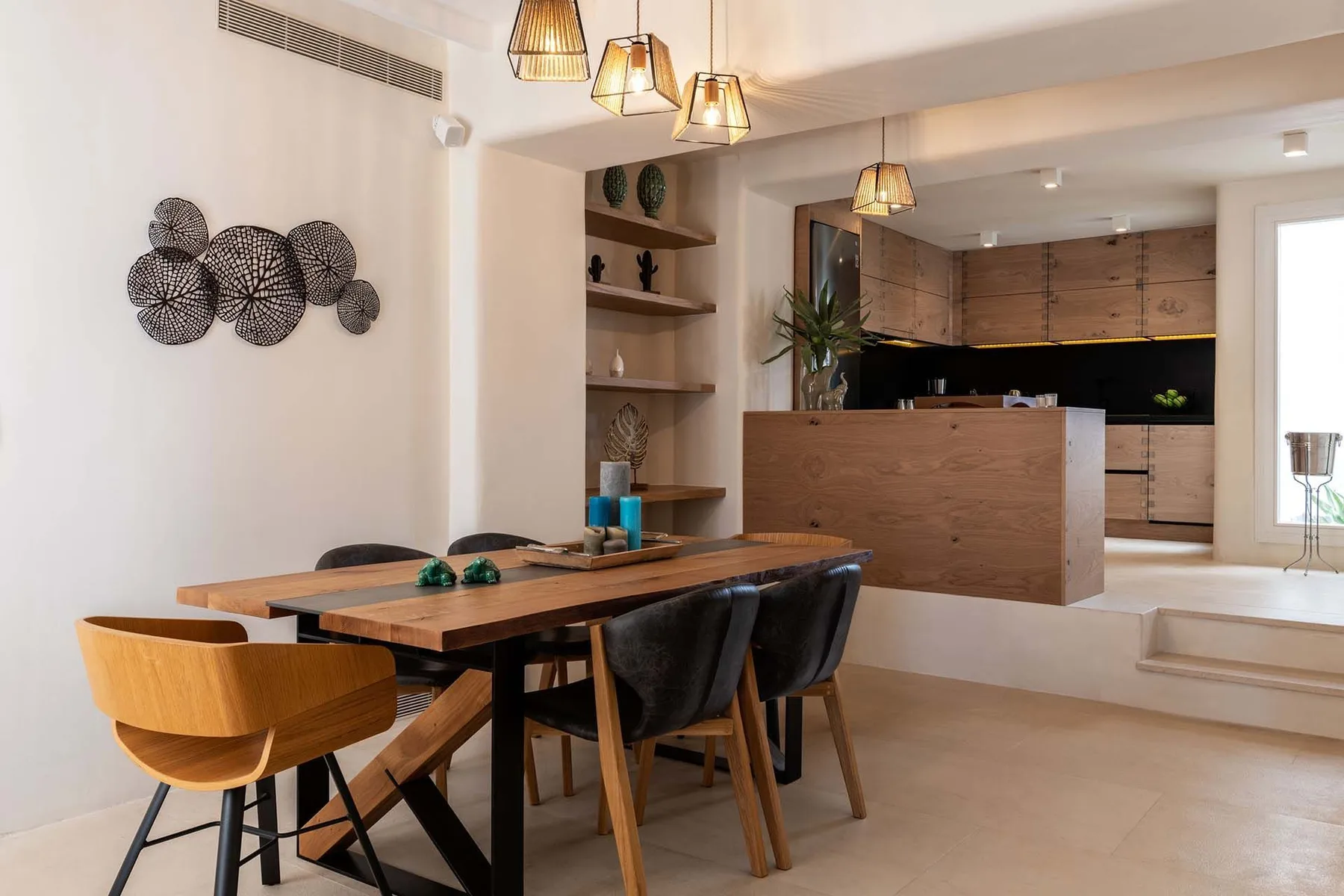 A dining area opens onto a kitchen, with a wooden table and seating.